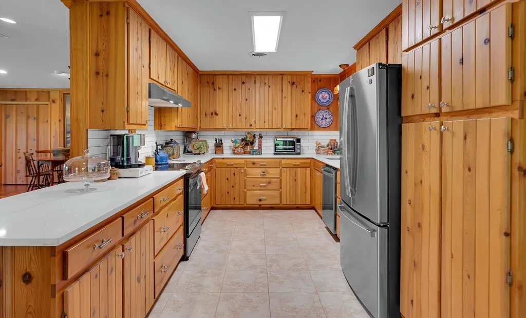 effecient and Qualityquality describes this kitchen featuring expensive wood cabinetry, well matched  countertops, tile flooring, and stainless steel appliances