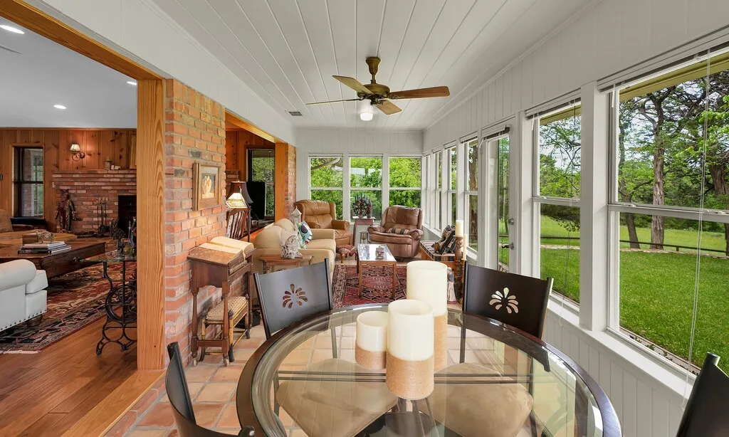 The sunroom features extensive windows, a ceiling fan, and tiled flooring