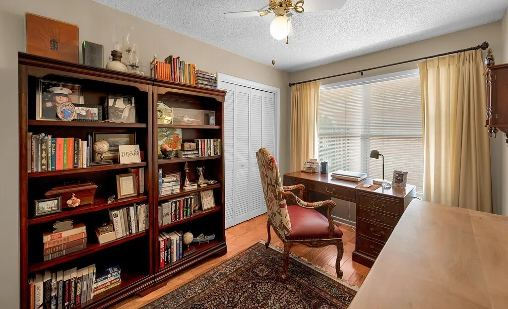 This room features hardwood flooring, a ceiling fan wall of natural light