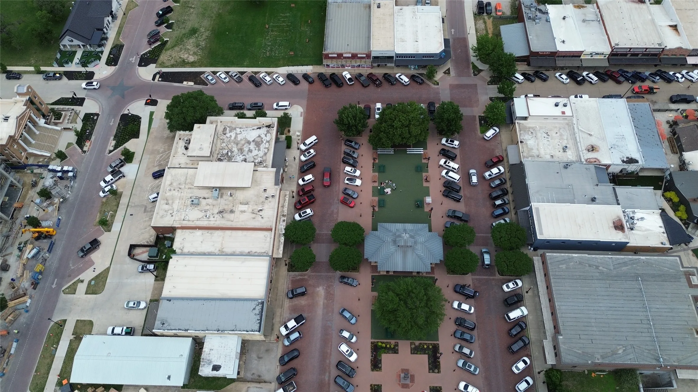 Aerial view of the community square featuring a central gazebo, paved pedestrian areas, and surrounding green spaces with mature trees