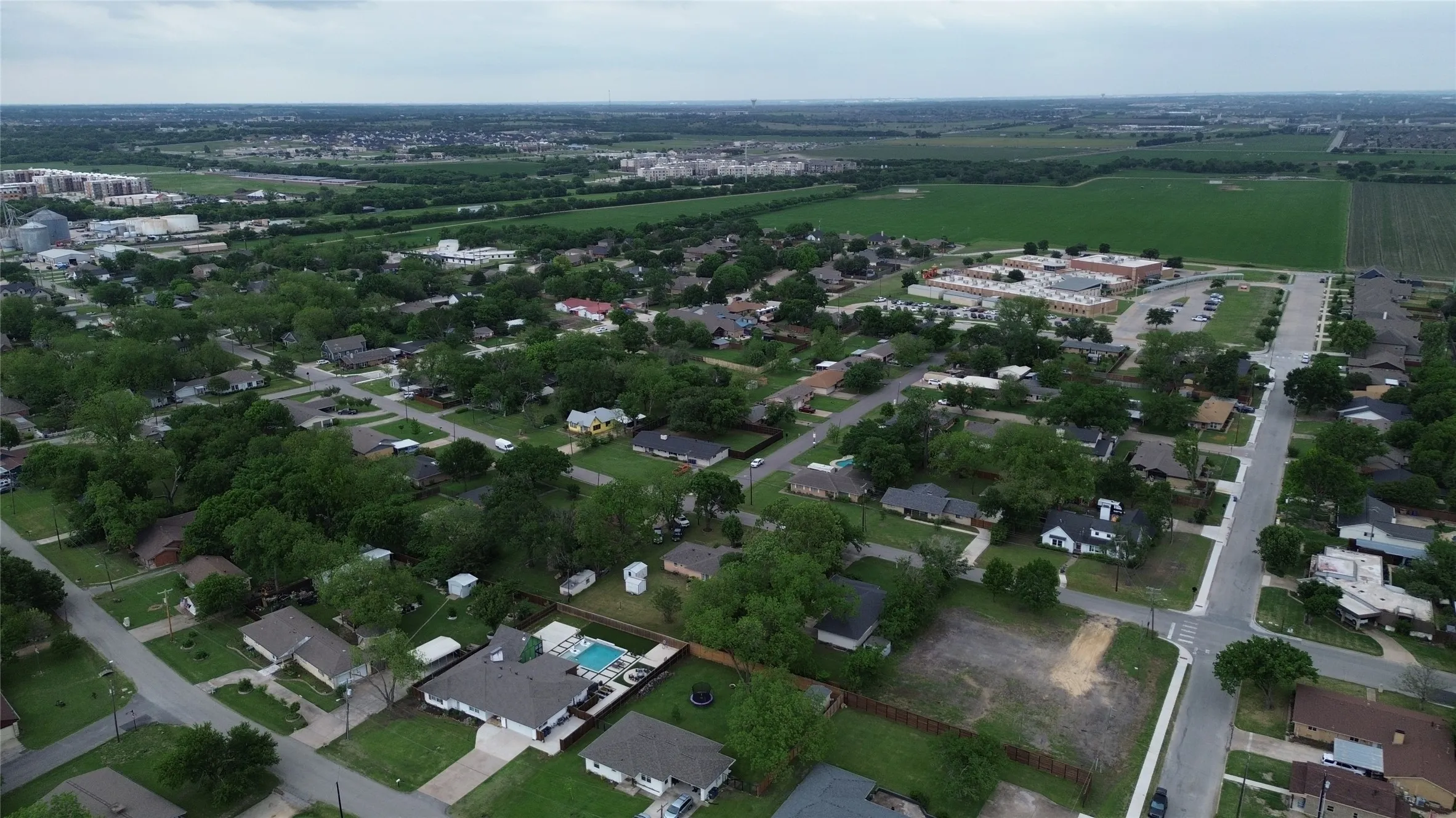 Aerial view of a residential area with streets, houses, and abundant trees