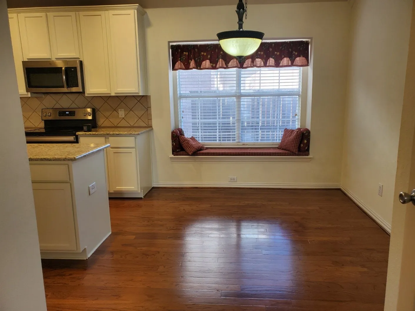 Kitchen and dining area featuring wood-finish flooring, a built-in window seat, and a kitchen island with granite countertops