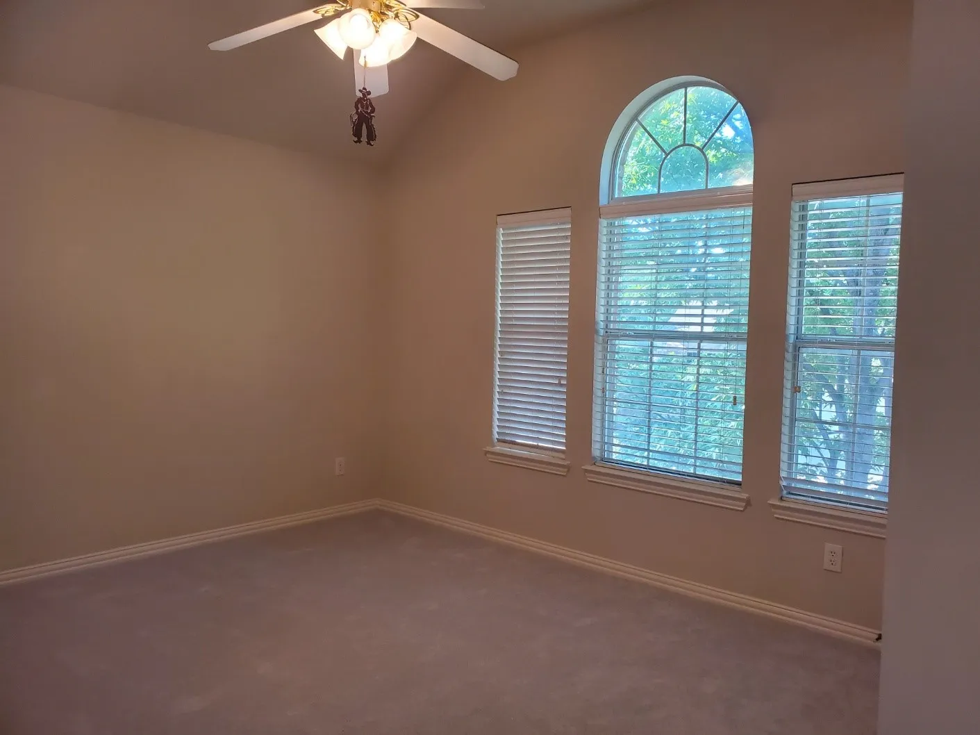 Room featuring an arched window, two rectangular windows with blinds, a vaulted ceiling, and a ceiling fan