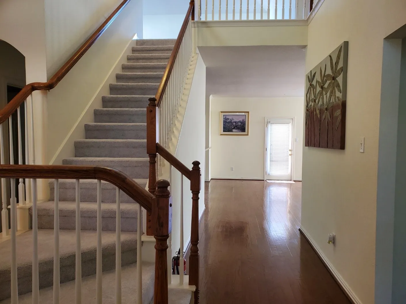Two-story foyer featuring hardwood-finish flooring and a staircase with carpeted treads