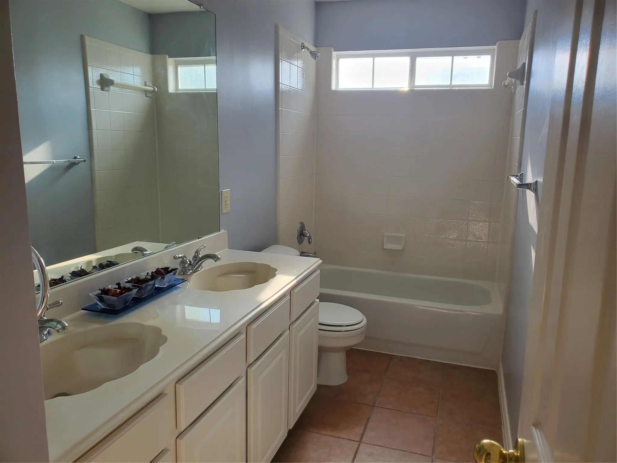 Bathroom featuring a dual vanity with integrated sinks, a combination tub and shower, tiled flooring, and a transom window