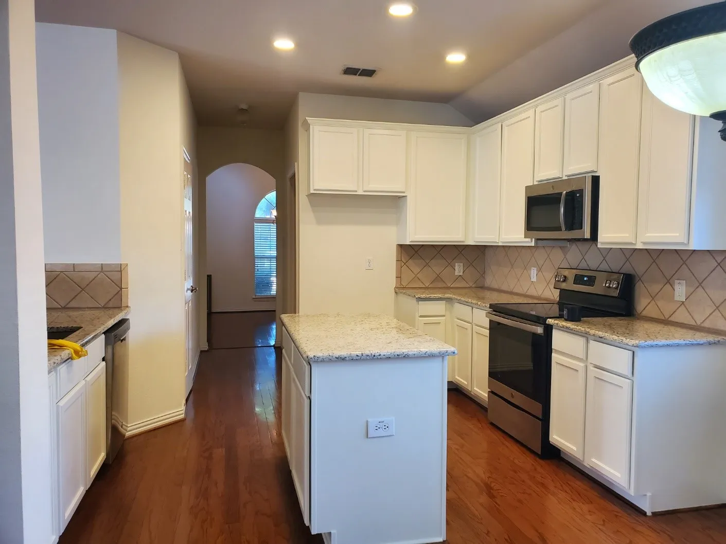Modern kitchen featuring white cabinetry, granite countertops, and stainless steel appliances
