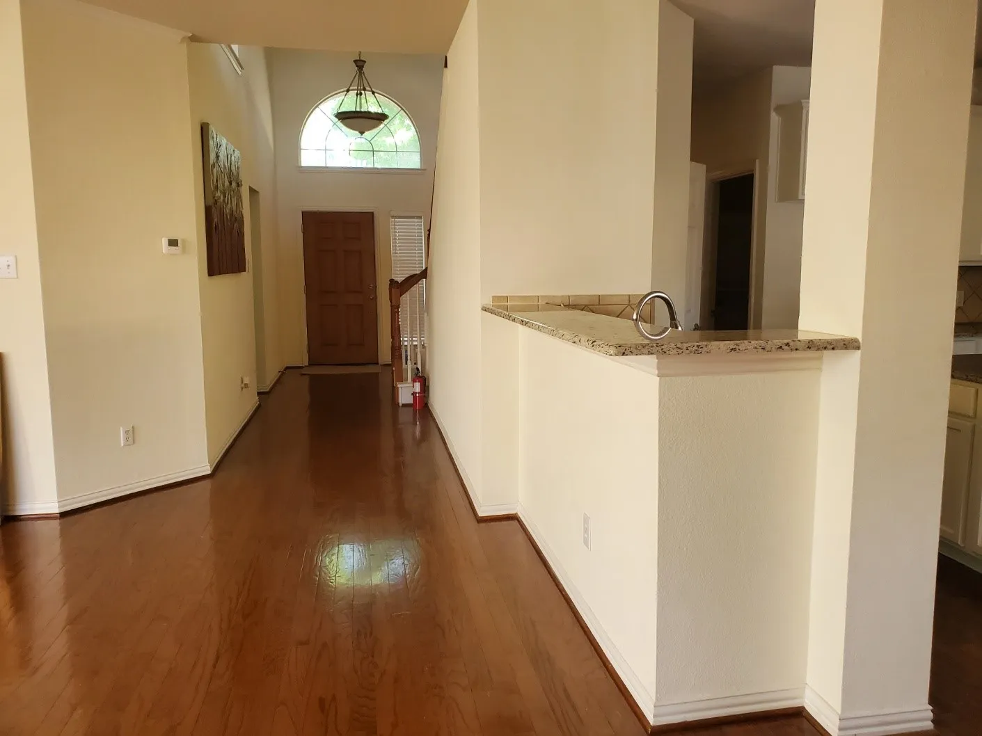 Foyer entry featuring wood-finish flooring, a vaulted ceiling, and an arched transom window