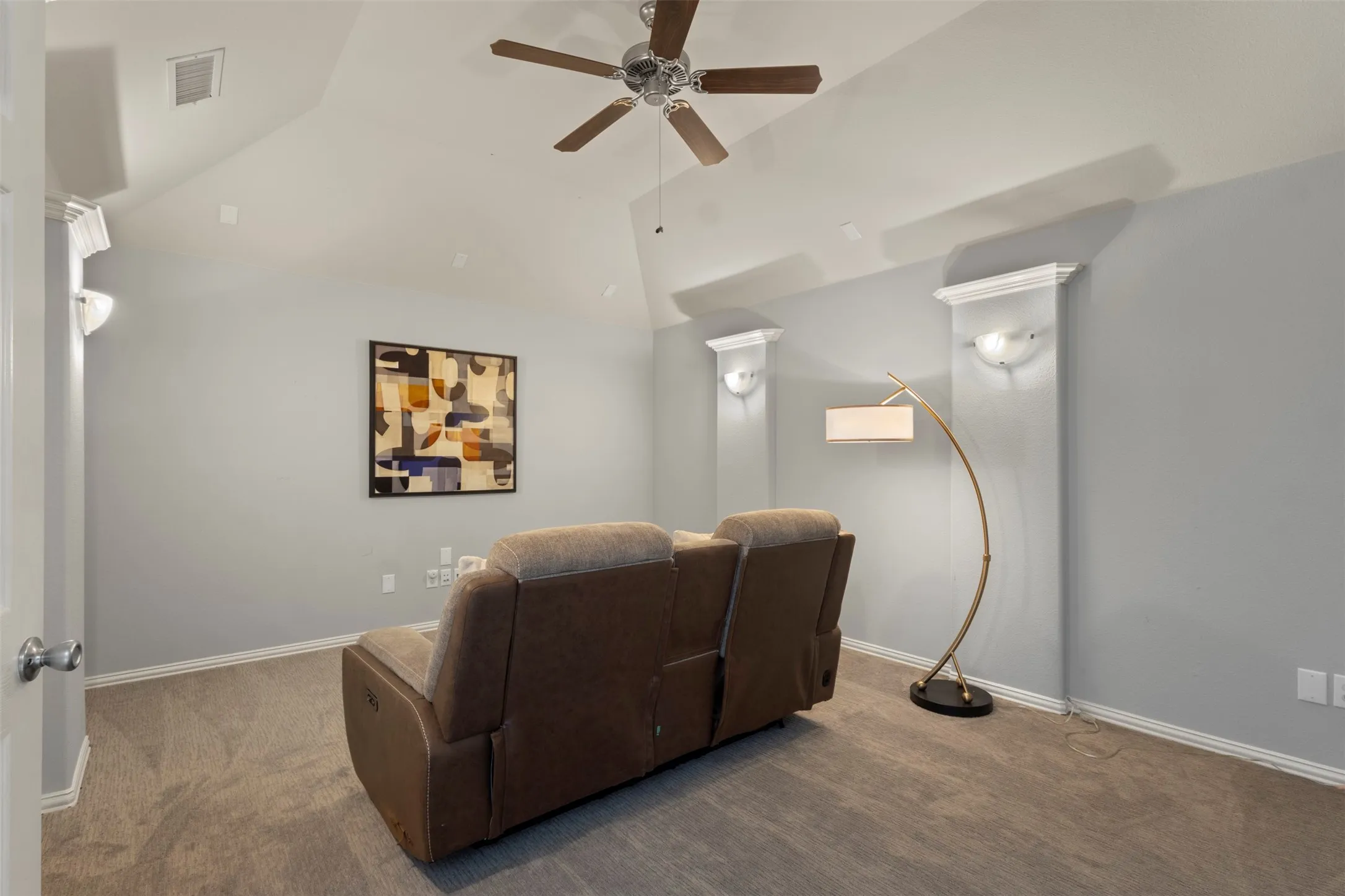 This room features vaulted ceilings, light gray walls, and carpet flooring