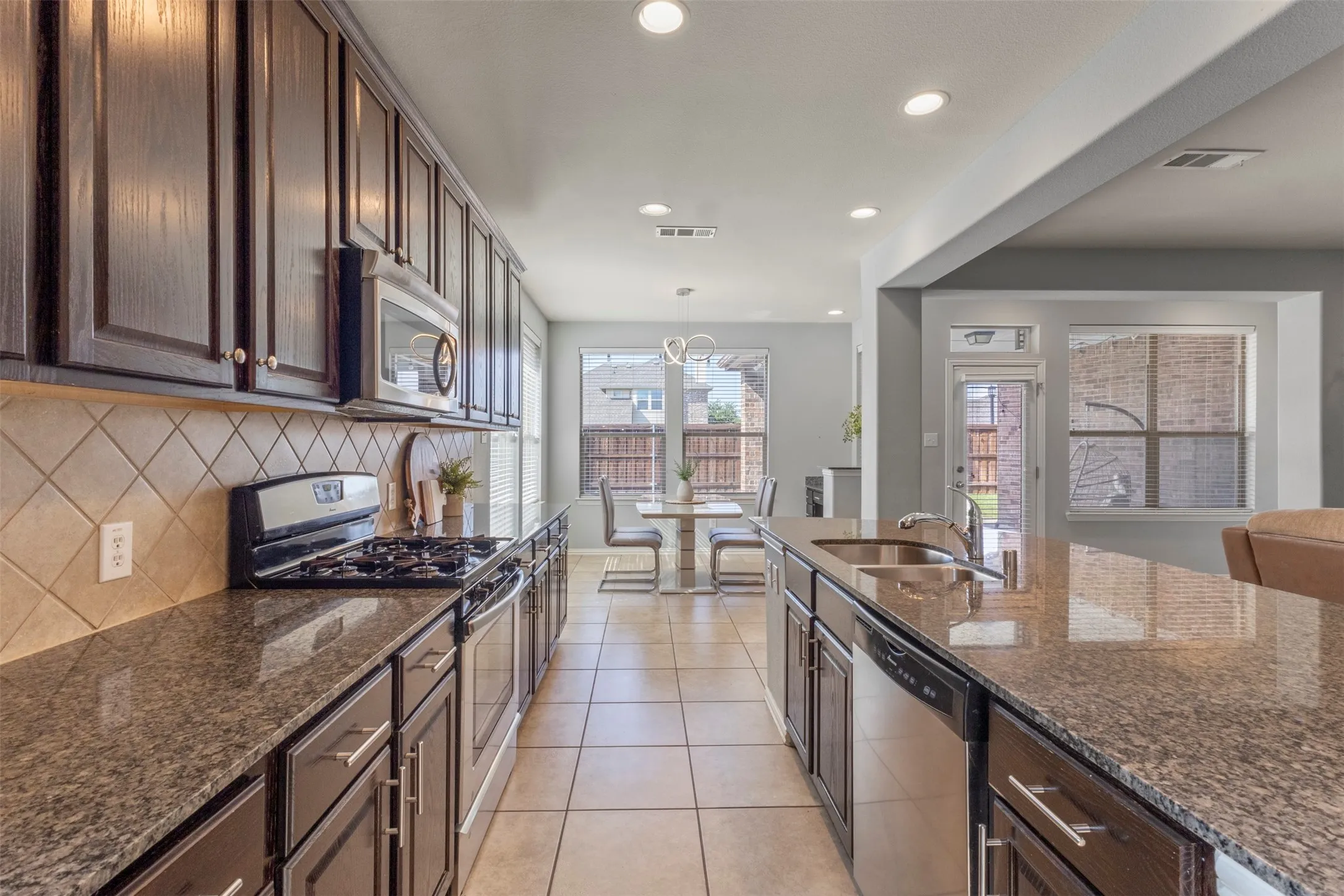 The kitchen features dark wood cabinetry, granite countertops, stainless steel appliances, and a tiled floor