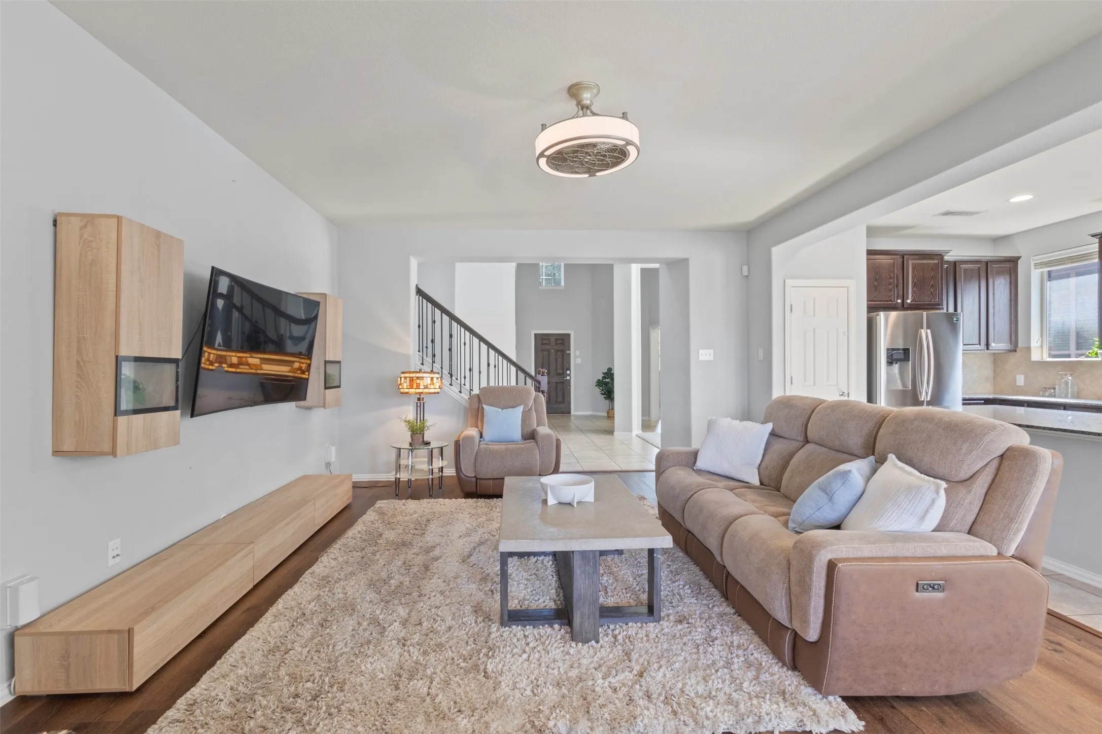 Open-concept living area featuring light-colored walls, wood flooring, and a ceiling light fixture
