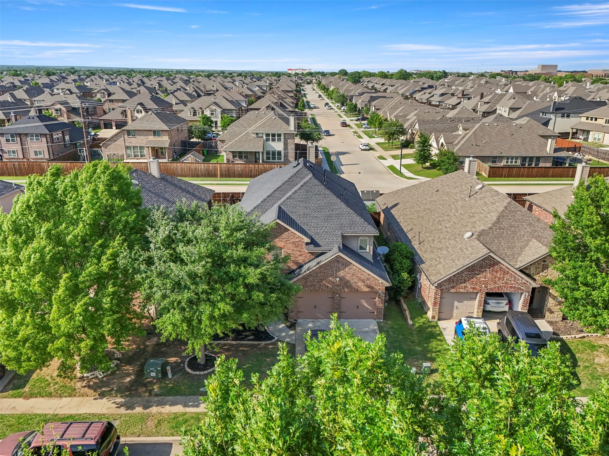 Aerial view of the property and its surrounding neighborhood, showcasing well-maintained homes with varied rooflines and a clear blue sky overhead