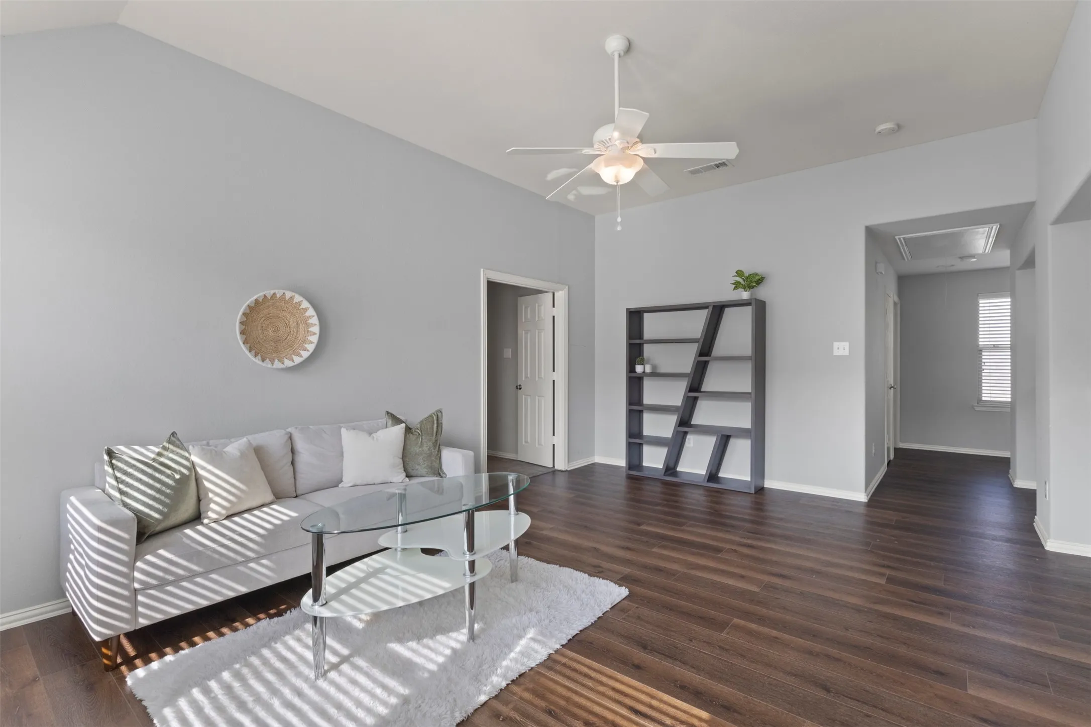 The living area features vaulted ceilings, dark wood-look flooring, and a ceiling fan