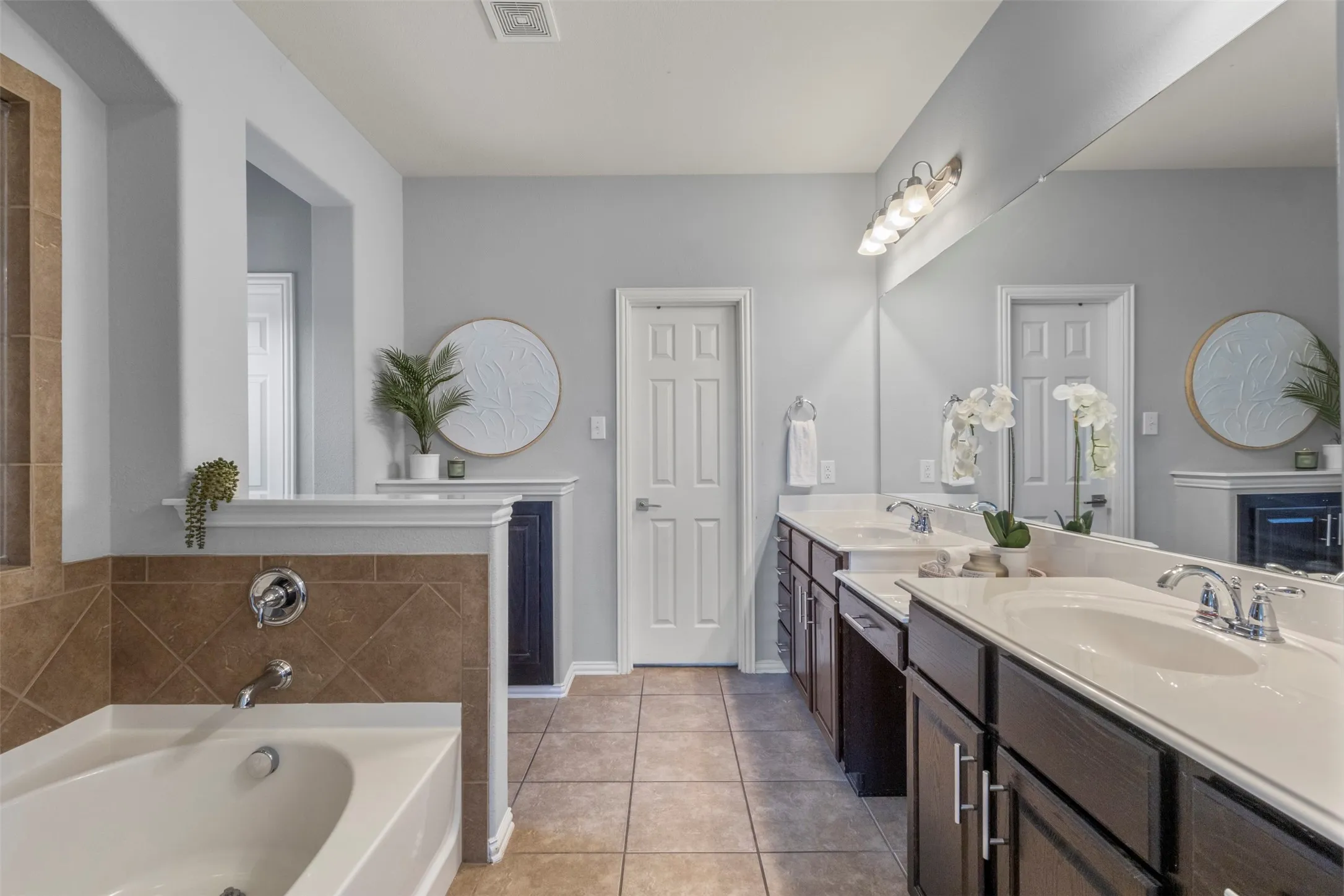 Bathroom featuring a white bathtub with chrome fixtures, tiled surround, and tiled flooring