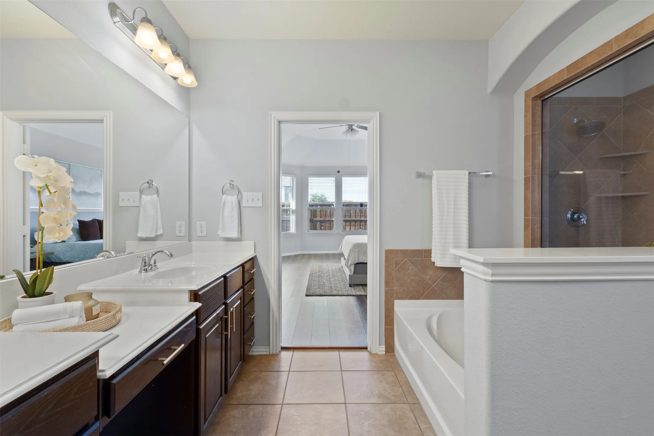 The bathroom features a double vanity with ample counter space, a built-in bathtub, and a separate shower with tiled walls