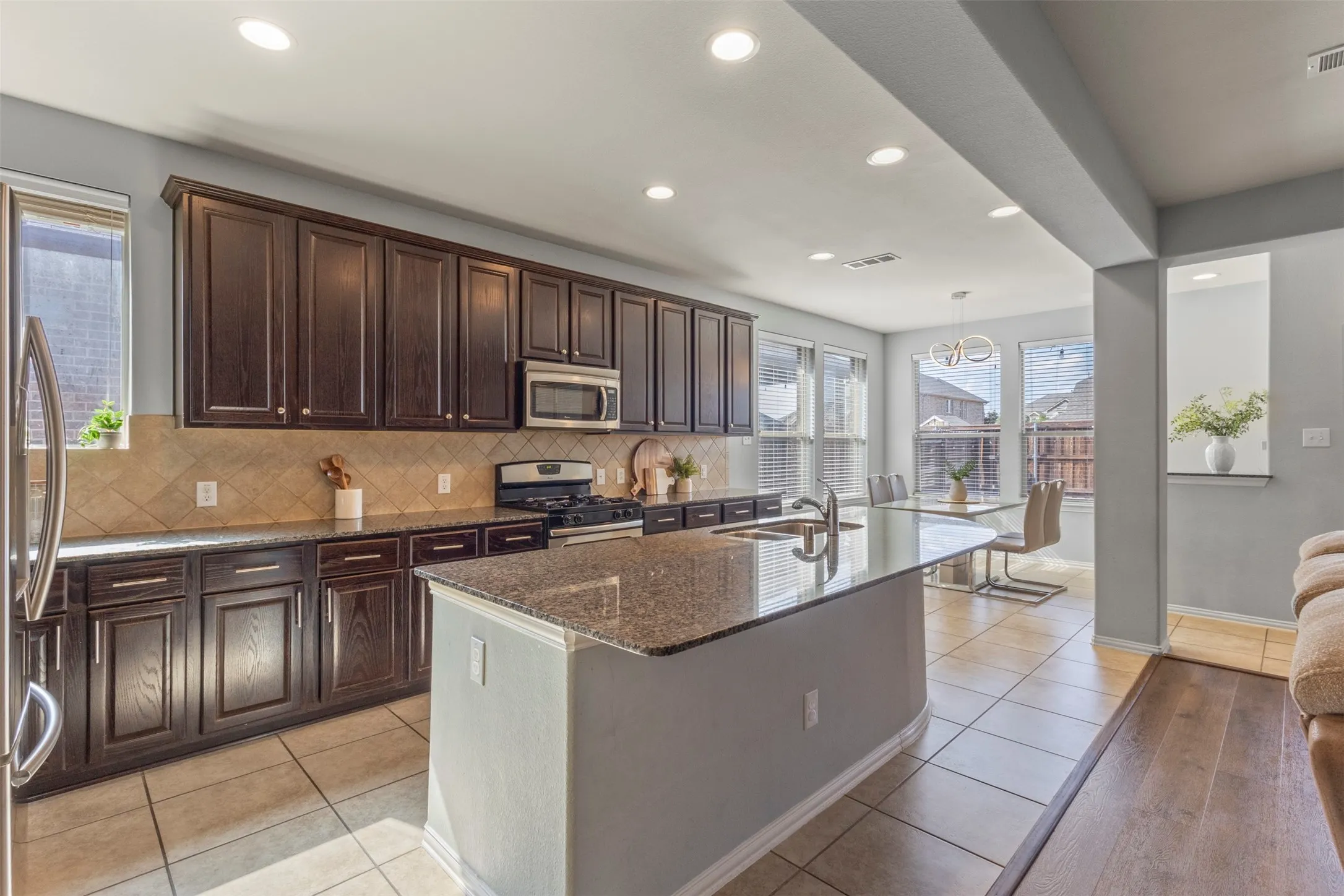 Well-appointed kitchen featuring dark wood cabinetry, granite countertops, and a tile backsplash