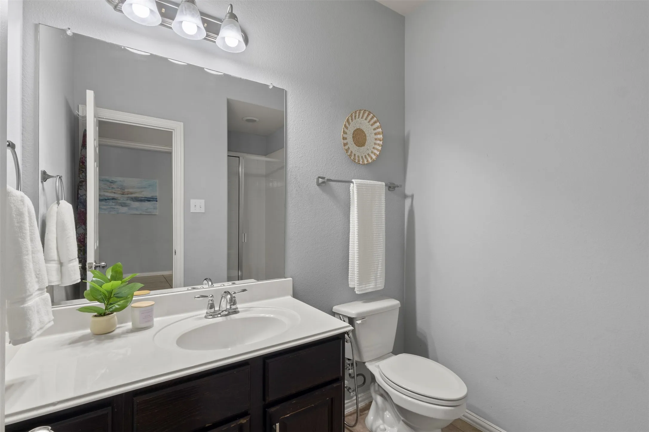 Well-appointed bathroom featuring a vanity with a white countertop, an integrated sink, and dark wood cabinetry