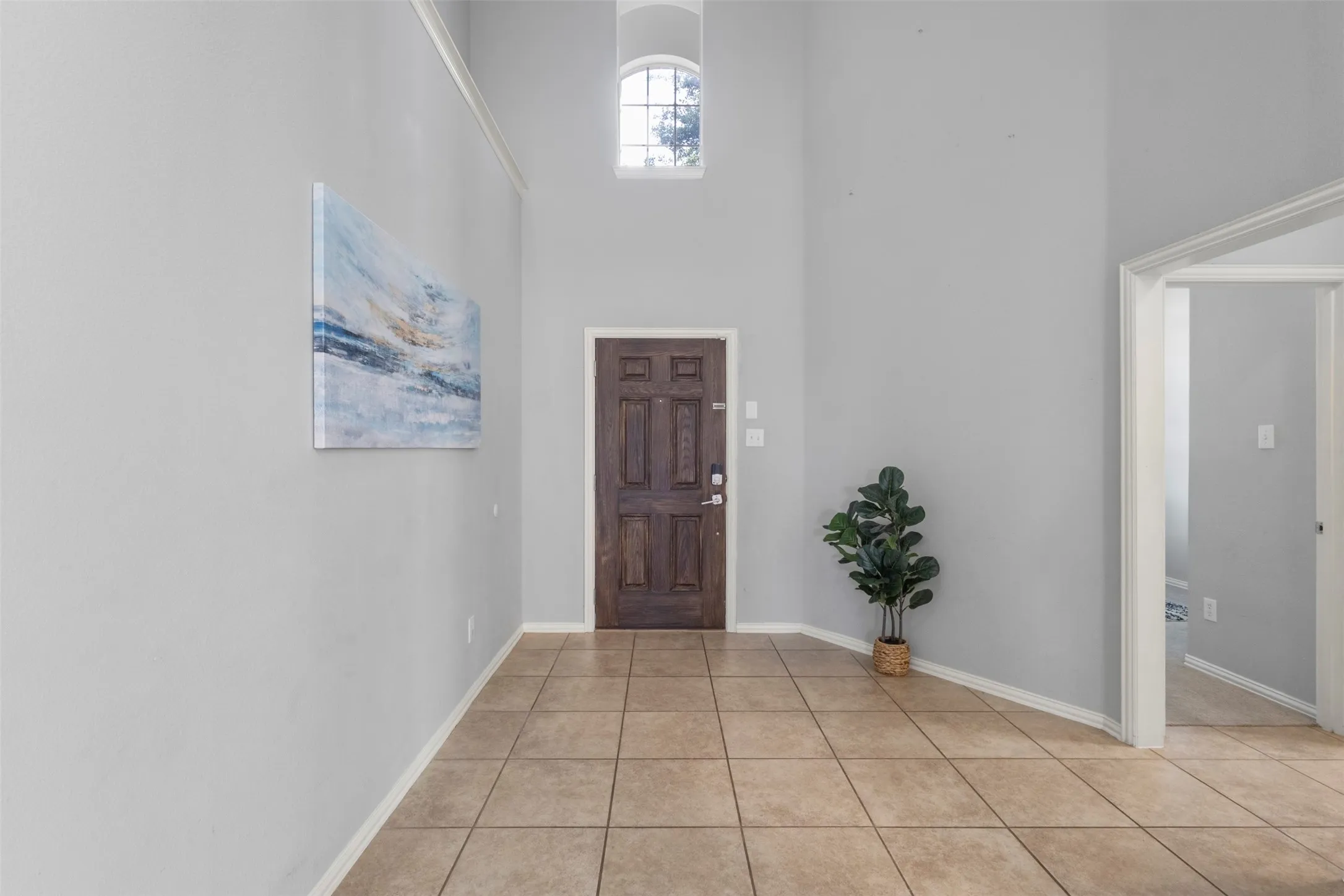 Entryway featuring high ceilings, a decorative arch window, and tile flooring