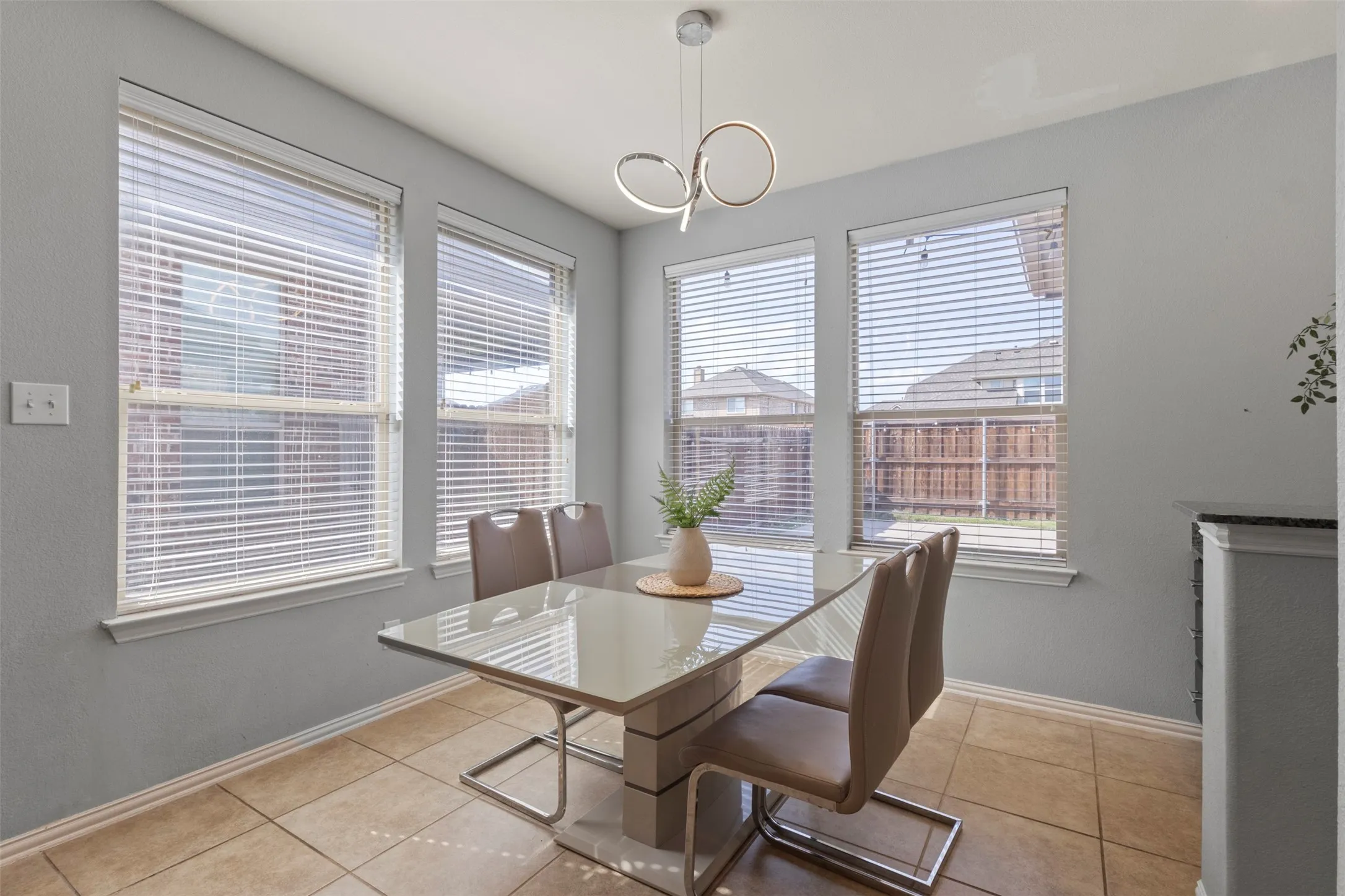 Dining area featuring tiled flooring, three windows with blinds, and a contemporary light fixture