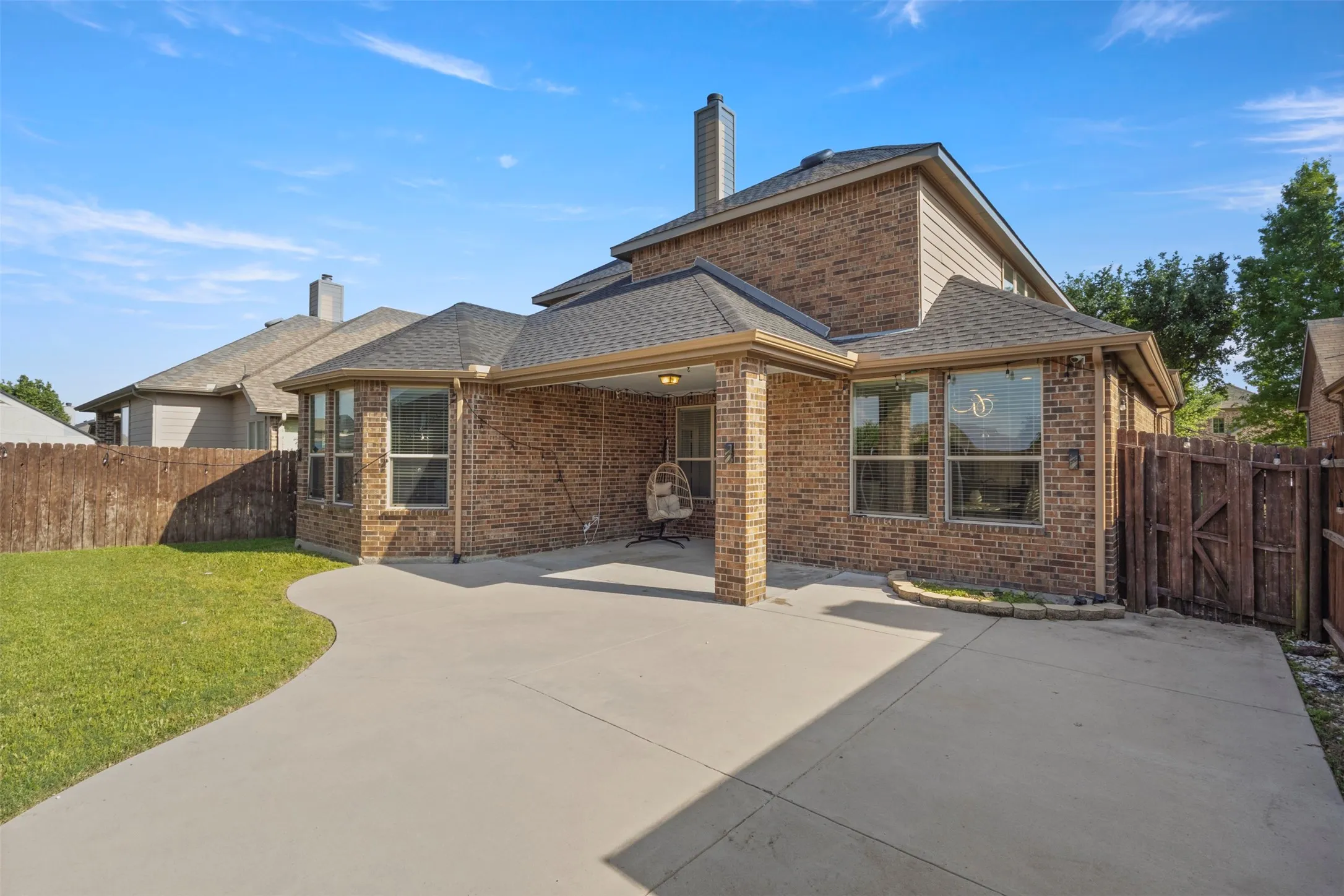 The property features a brick exterior, a covered patio area, and a private yard with a wooden fence
