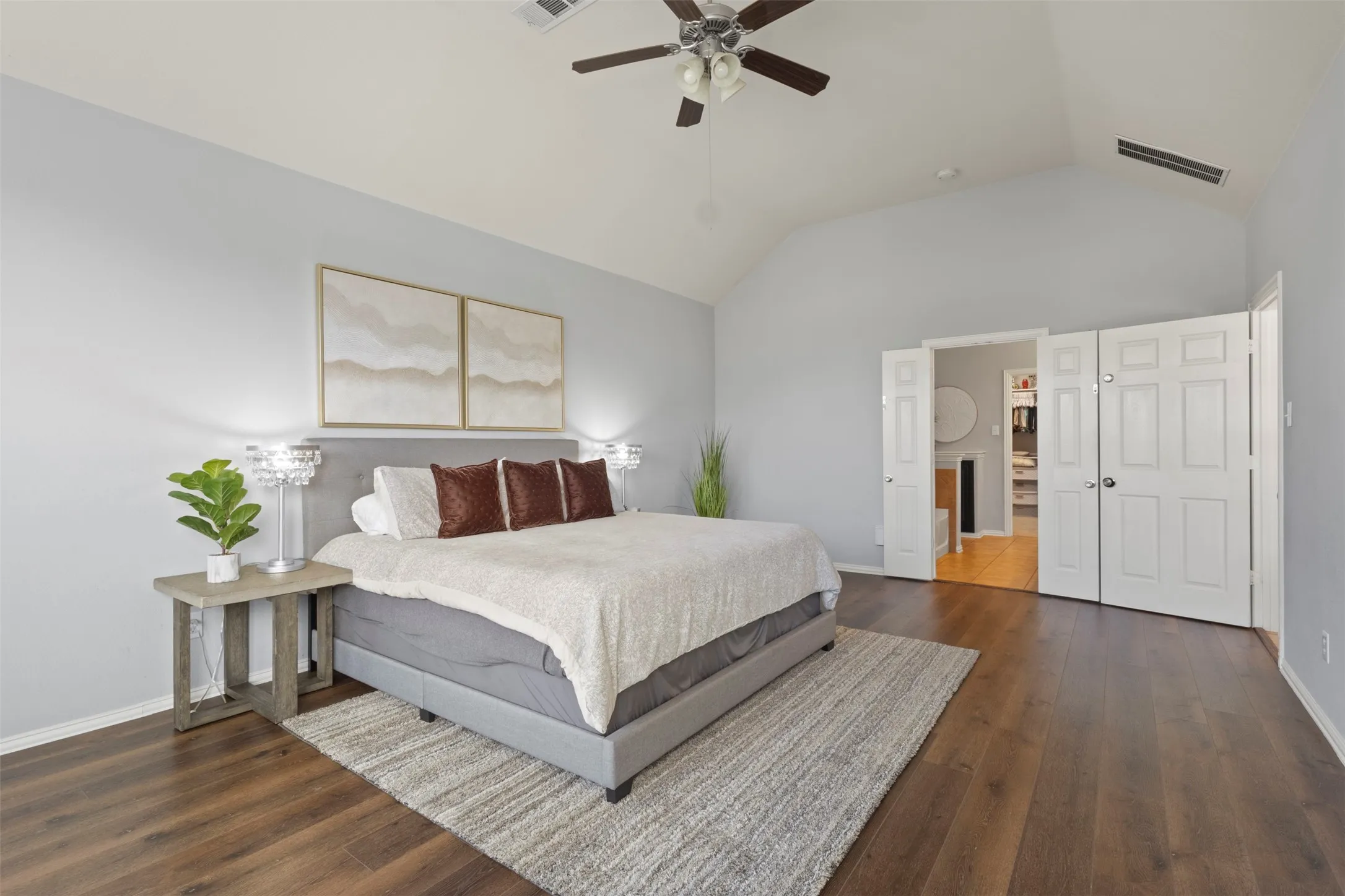 This bedroom features hardwood style flooring, a vaulted ceiling, and a ceiling fan