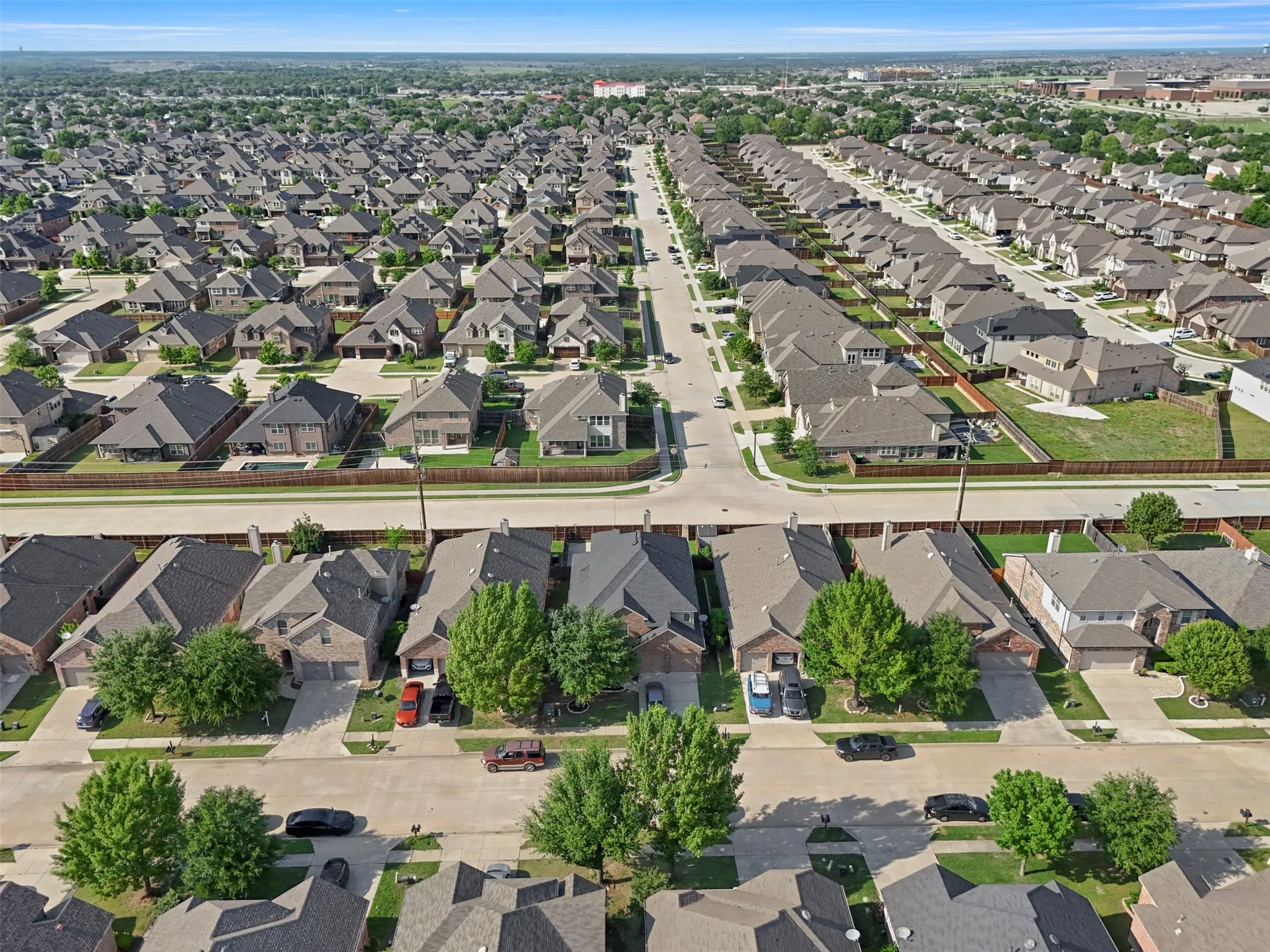 Aerial view of the neighborhood showcasing a collection of properties with varied architectural styles, mature trees, and fences defining the property lines