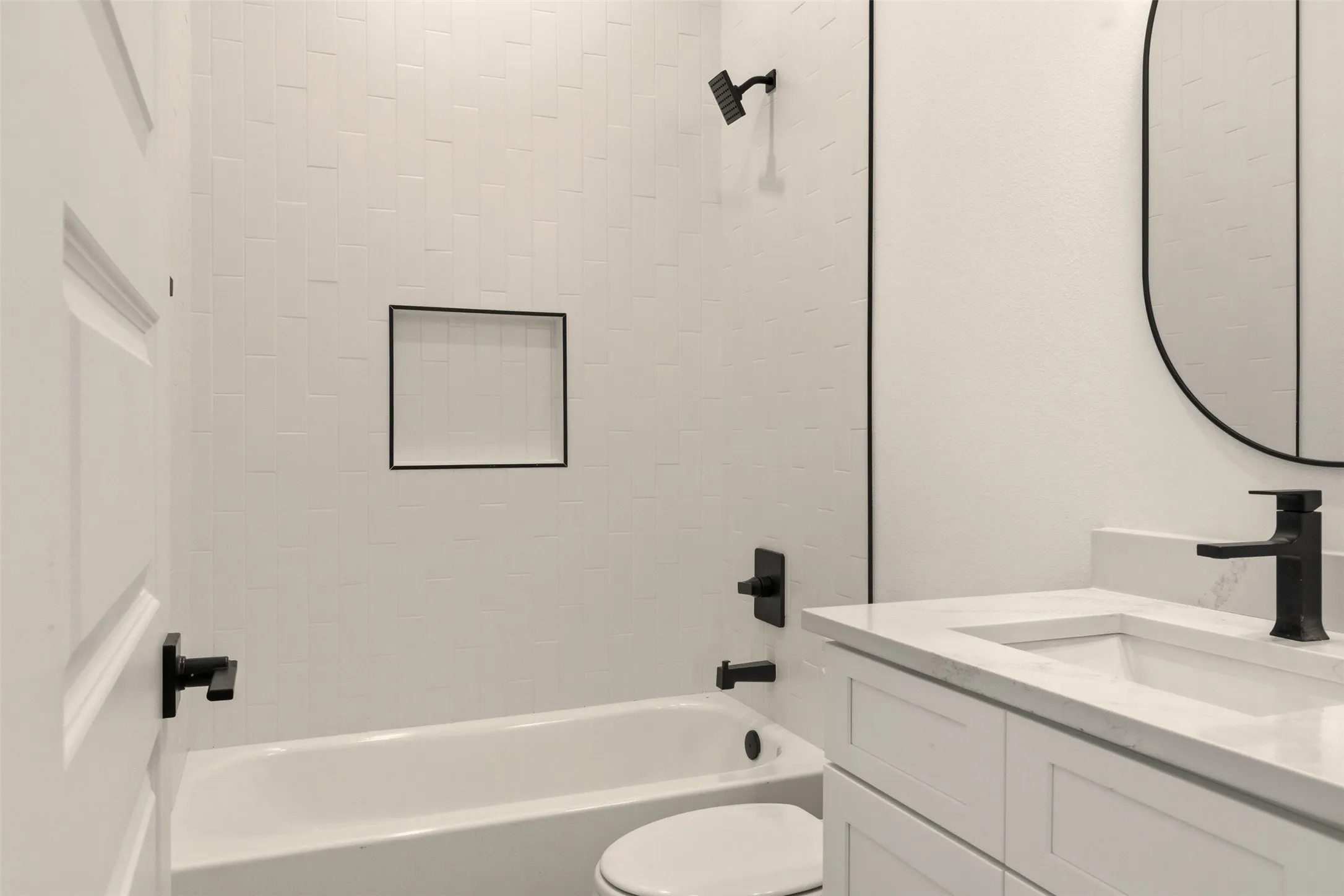The bathroom features a white bathtub with subway tile surround, a built-in shower niche, and a vanity with a white countertop and sink