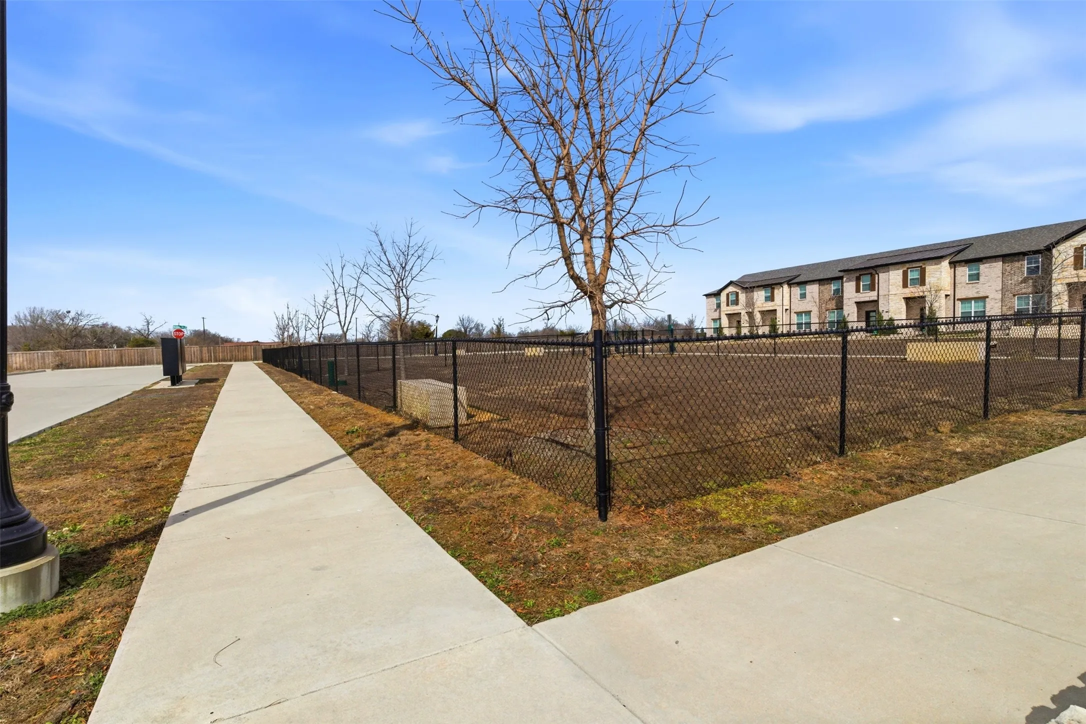 The property features a concrete walkway and a fenced area with visible trees