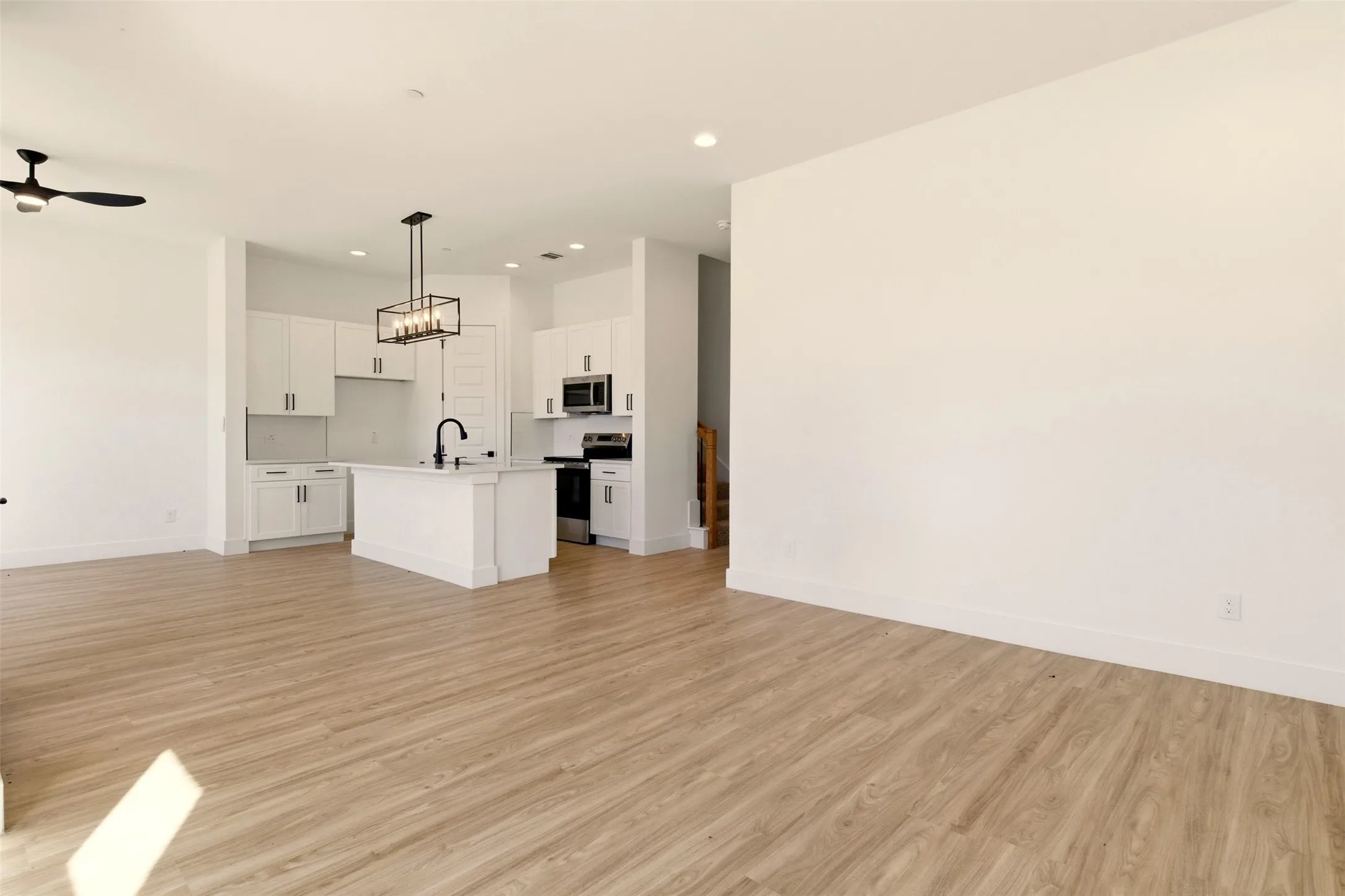Open concept living space featuring light-toned flooring, white walls, and recessed lighting