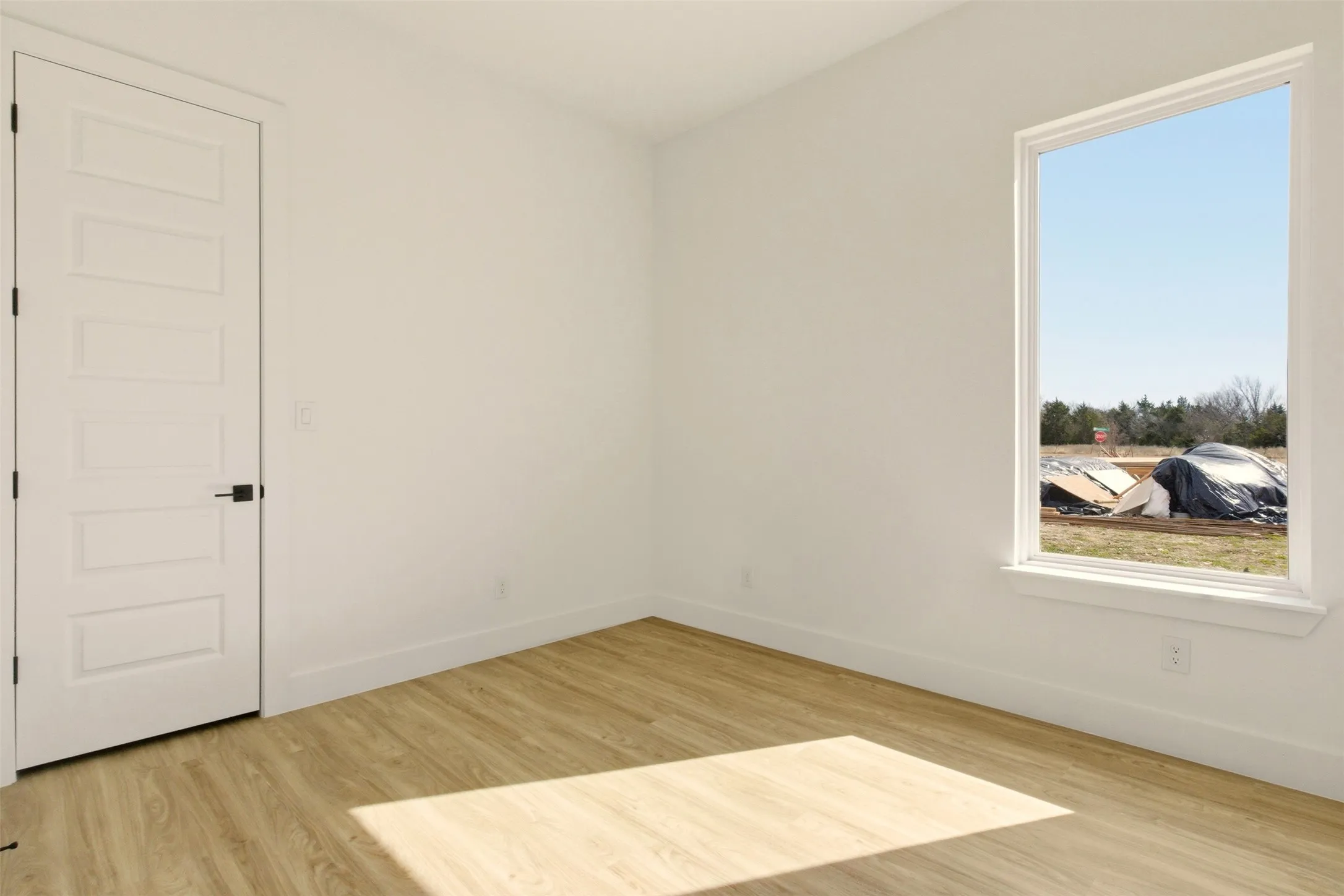 This room features light-colored flooring, white walls, and a white interior door with a black handle