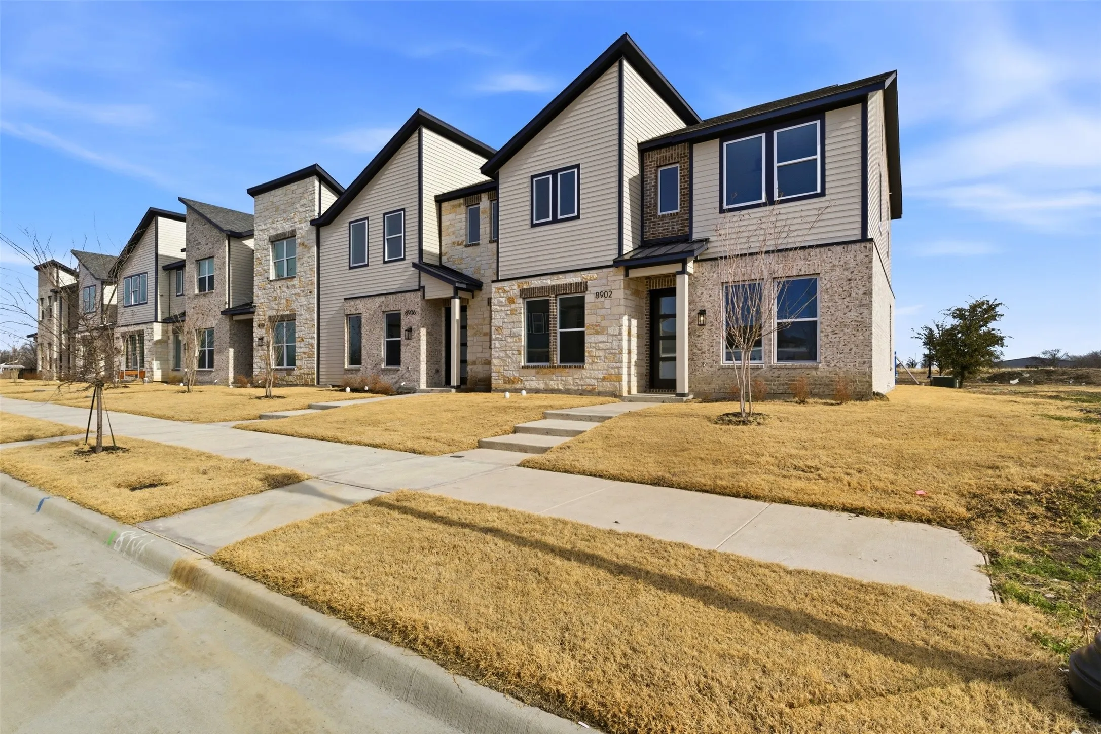 The property features a modern exterior with a blend of light-colored siding and stone accents, complemented by dark trim around the windows and rooflines