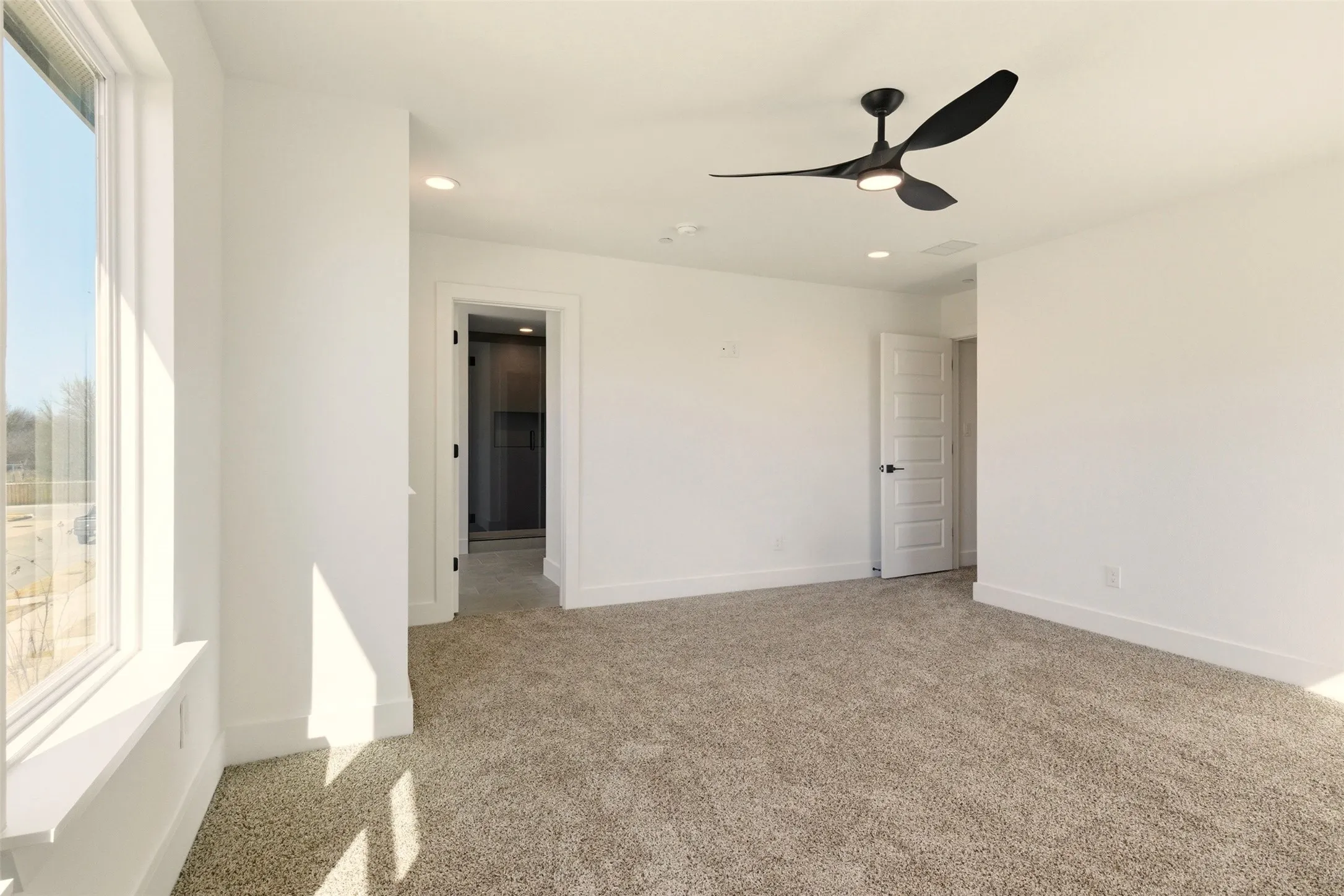 This room features a window providing natural light, a ceiling fan with integrated lighting, recessed lighting, and neutral-toned carpeting