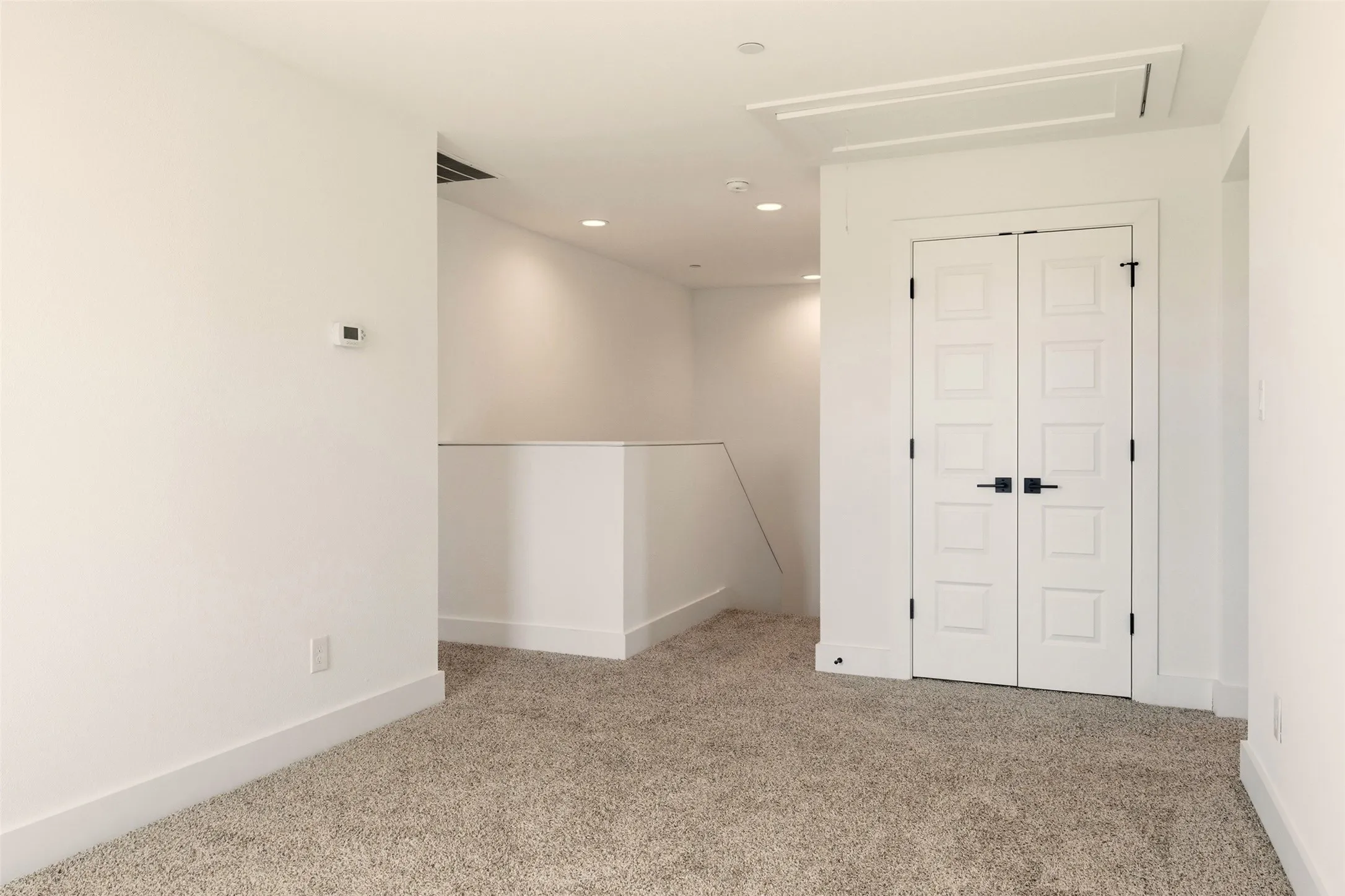 Living space featuring carpet flooring, white walls, recessed lighting, and a white double door
