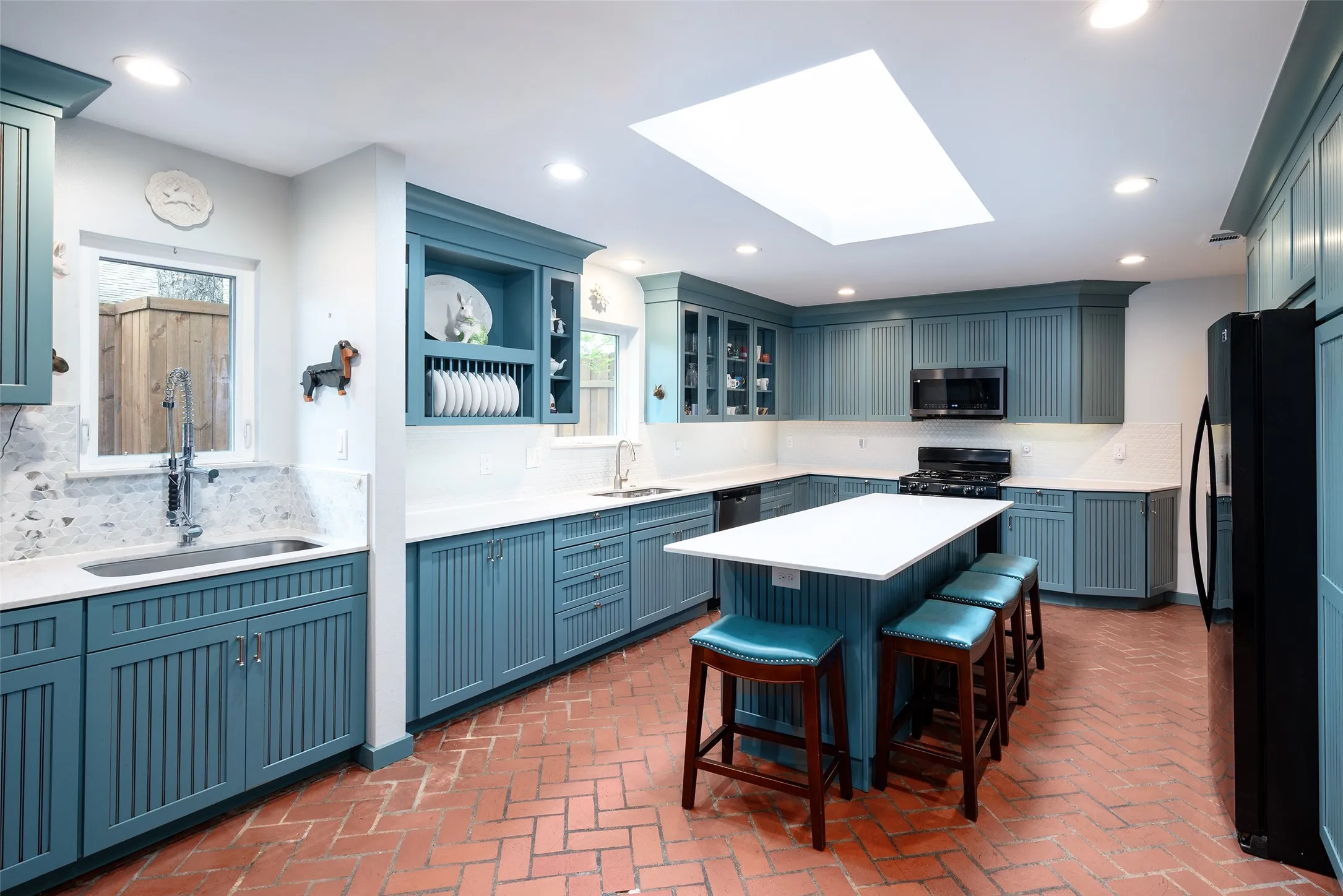 The kitchen features extensive blue cabinetry, white countertops, and a central island with bar seating