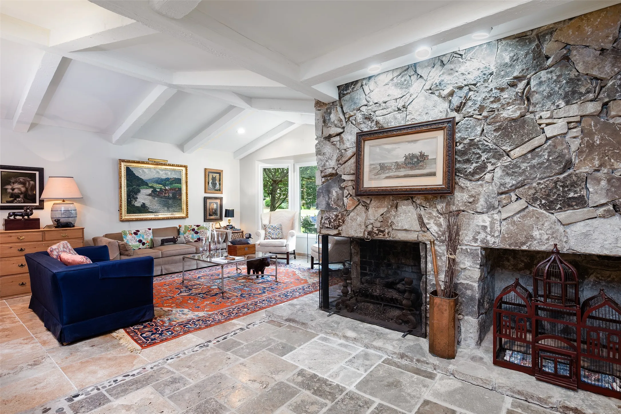 Living area featuring a stone fireplace, exposed beam vaulted ceilings, and natural stone flooring