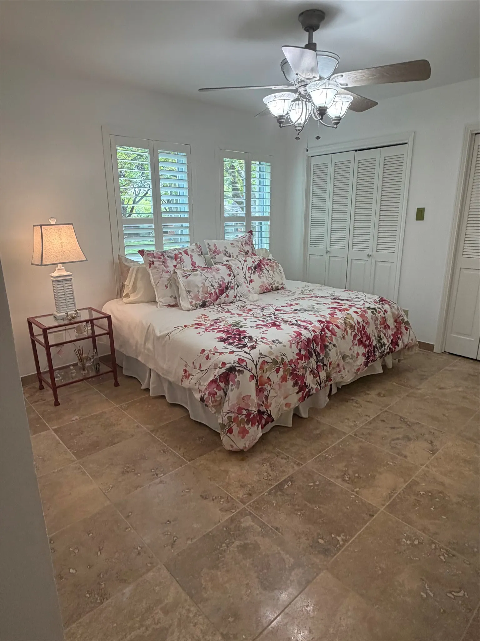 Refreshed painted walls. Travertine tile flooring, ceiling fan with integrated lighting, two windows with white louvered shutters, and bi-fold closet doors