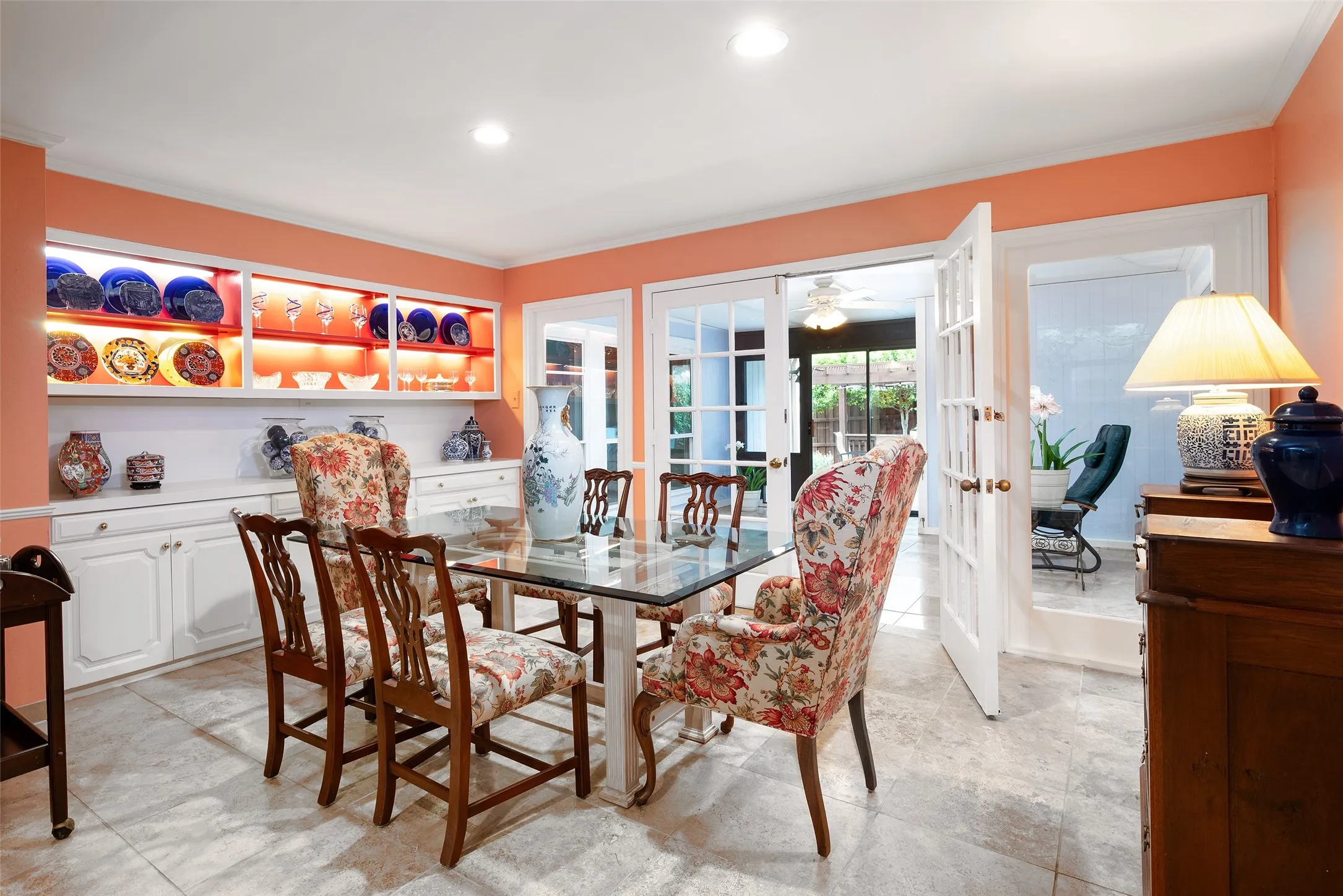 This dining area features tile flooring, built-in cabinetry with illuminated display shelves, and French doors