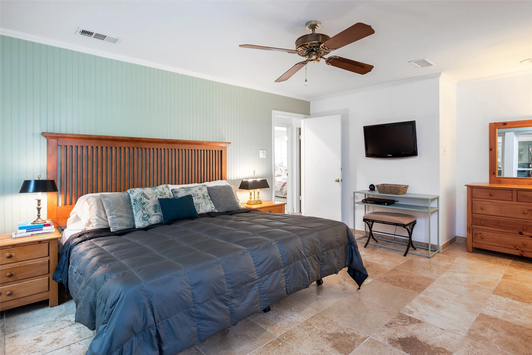 The bedroom features terrazzo flooring, a ceiling fan, and a light-colored accent wall