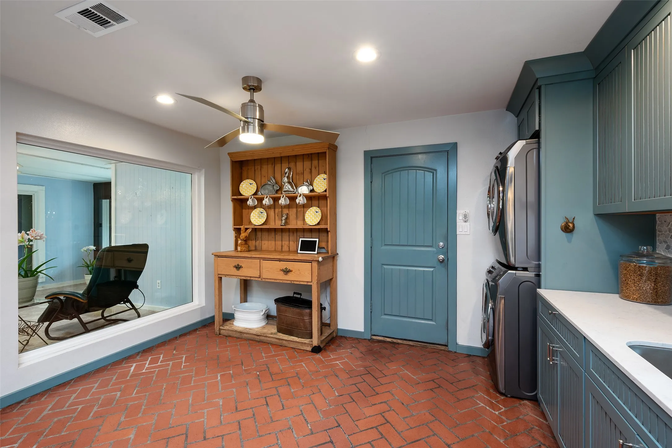 This versatile room features brick flooring, a large window providing views of the atrium, patterned brick flooring, new stacked full-sized washer dryer, and a ceiling fan for comfort