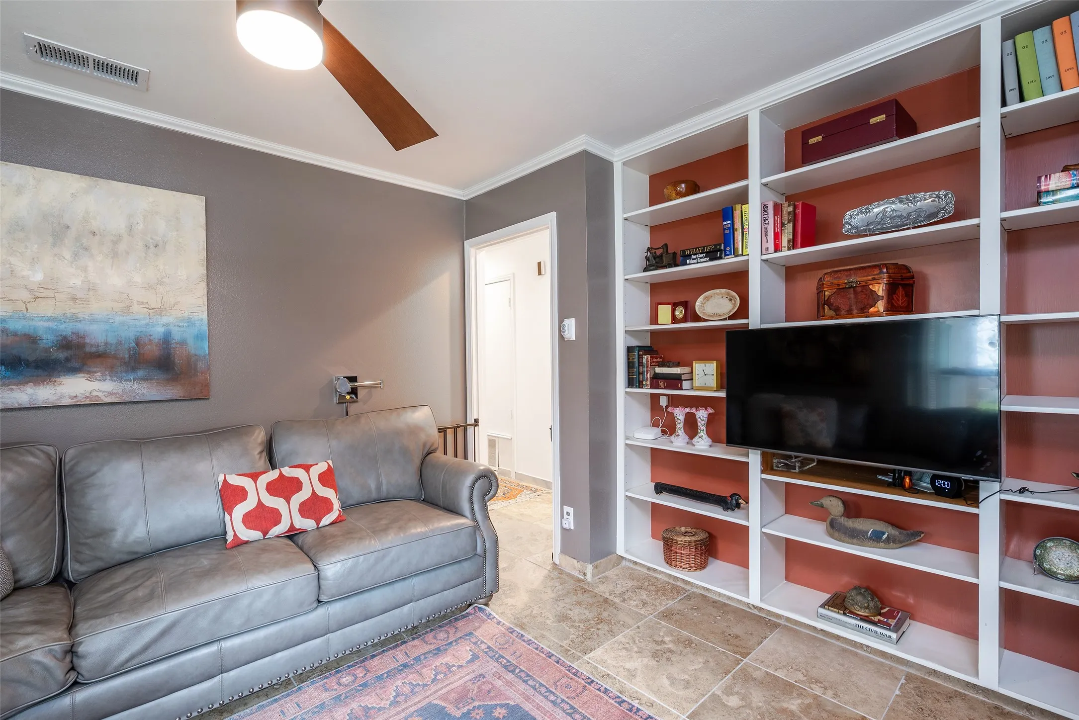 Living room featuring a ceiling fan, crown molding, and built-in shelving with an integrated television space