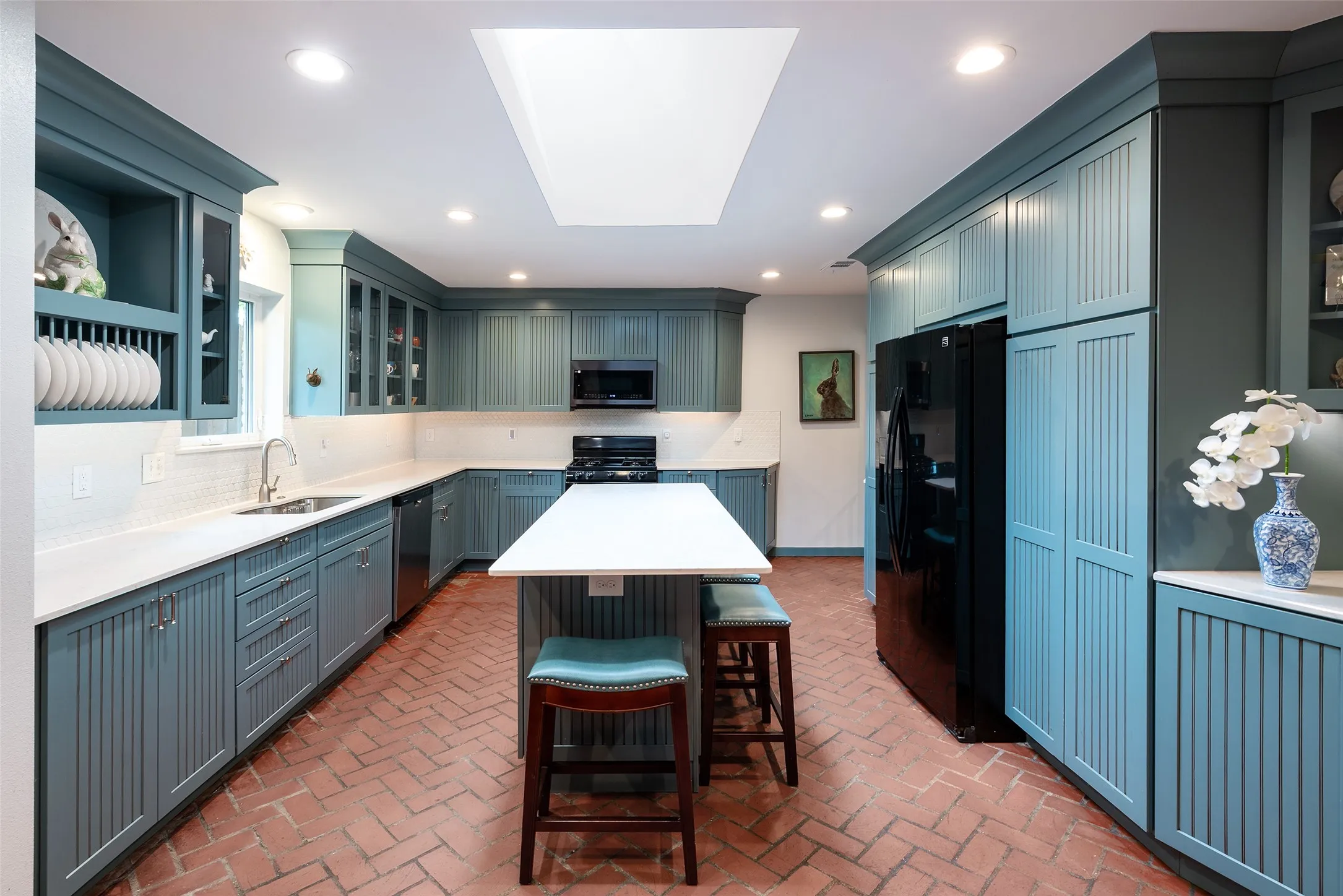 The kitchen features extensive blue cabinetry, white quartz countertops, and a brick-patterned floor