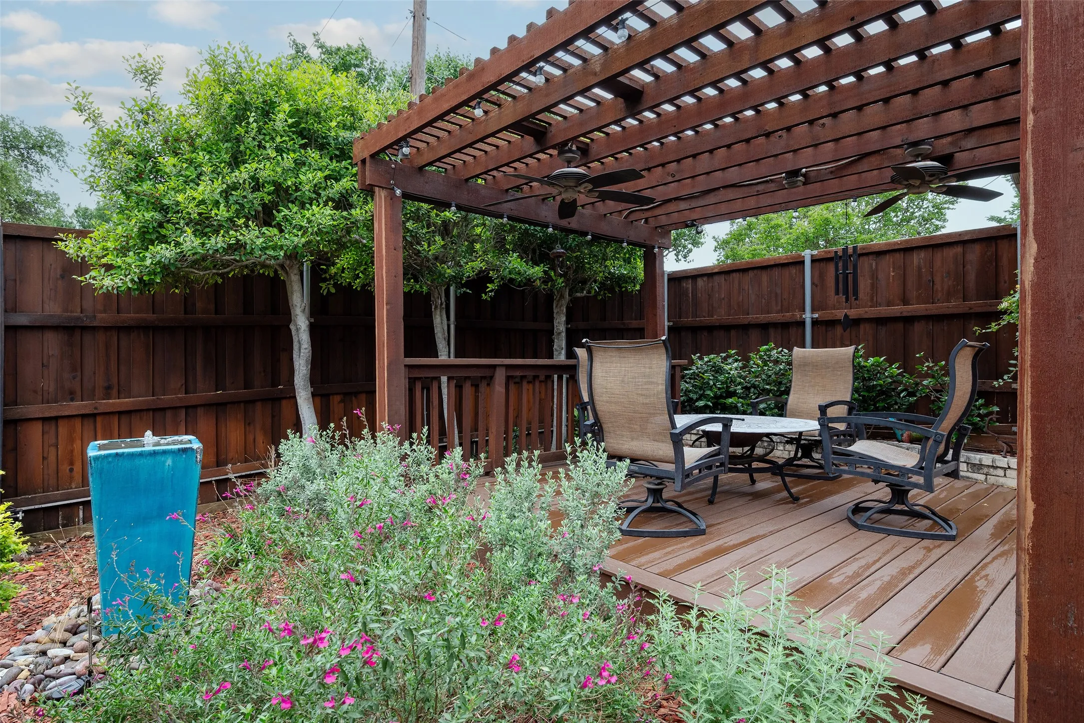 The outdoor area features a wooden deck with a slatted pergola, equipped with ceiling fans
