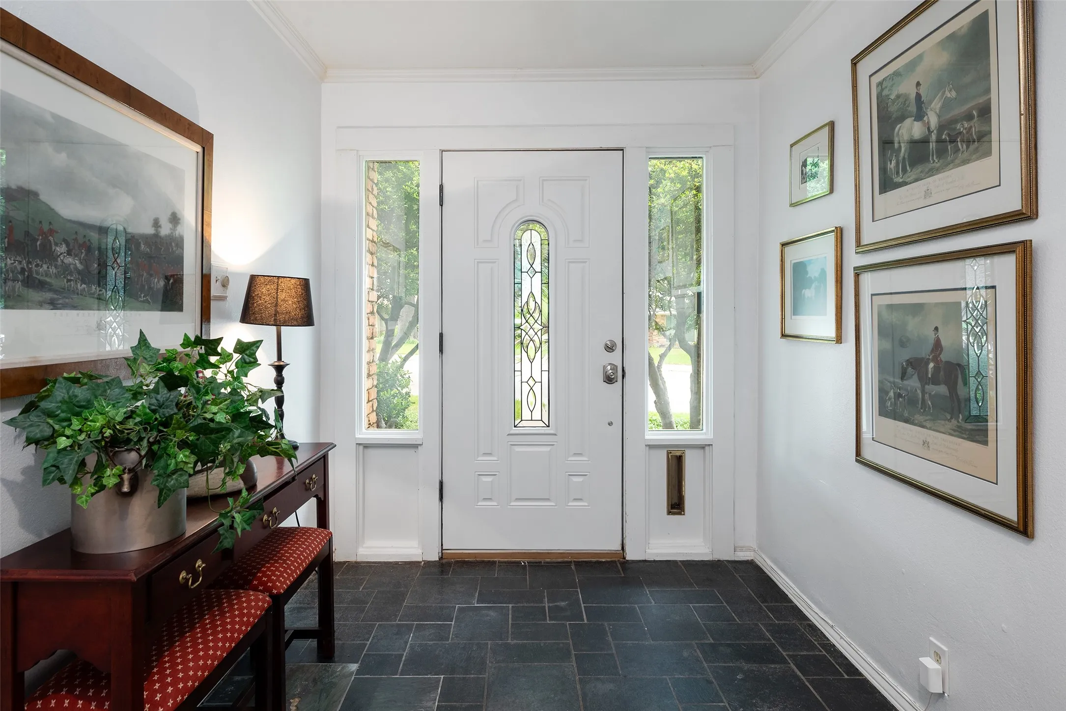 The entryway features a white door with decorative glass inserts, flanked by side windows that provide natural light and slate-tile floor.