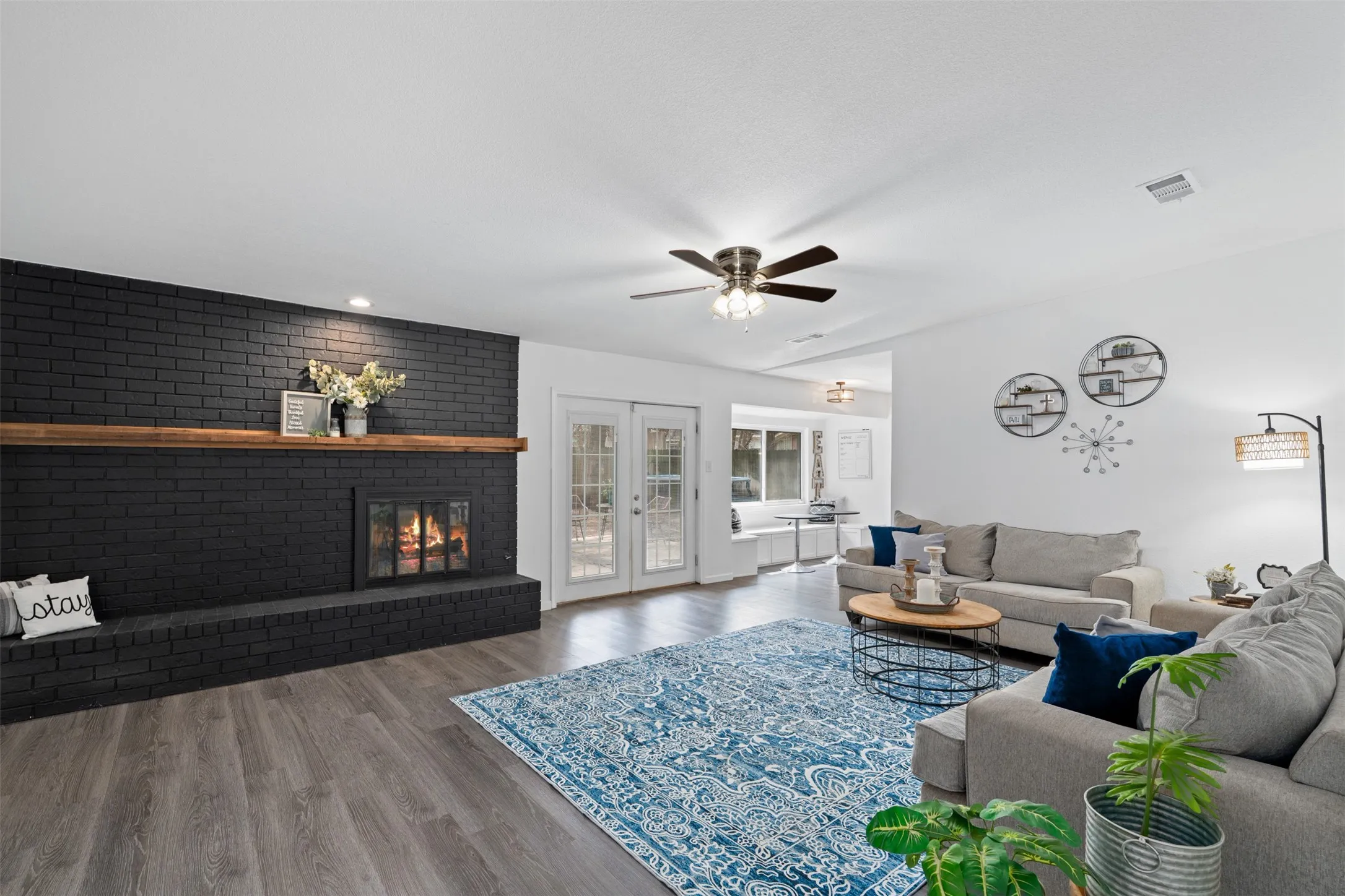 Large family room has a huge stunning black fireplace with wood mantle!