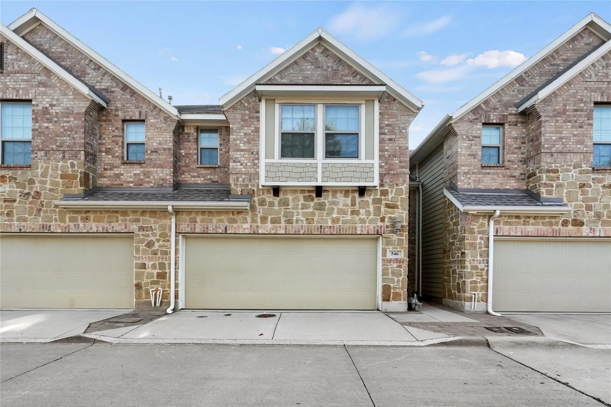 View of front of property with stone siding, driveway, and a garage