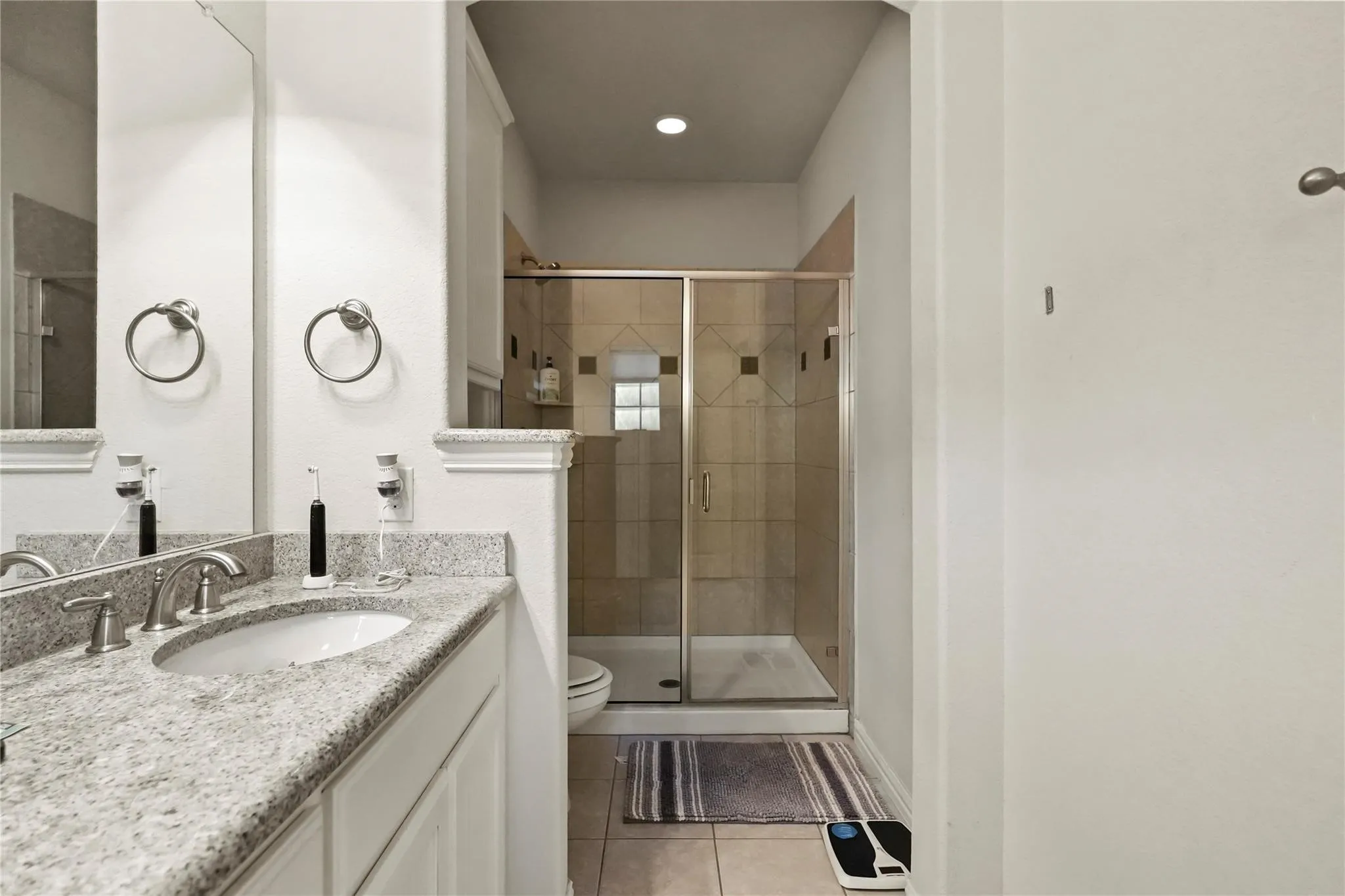 Full bath featuring vanity, a stall shower, and light tile patterned floors