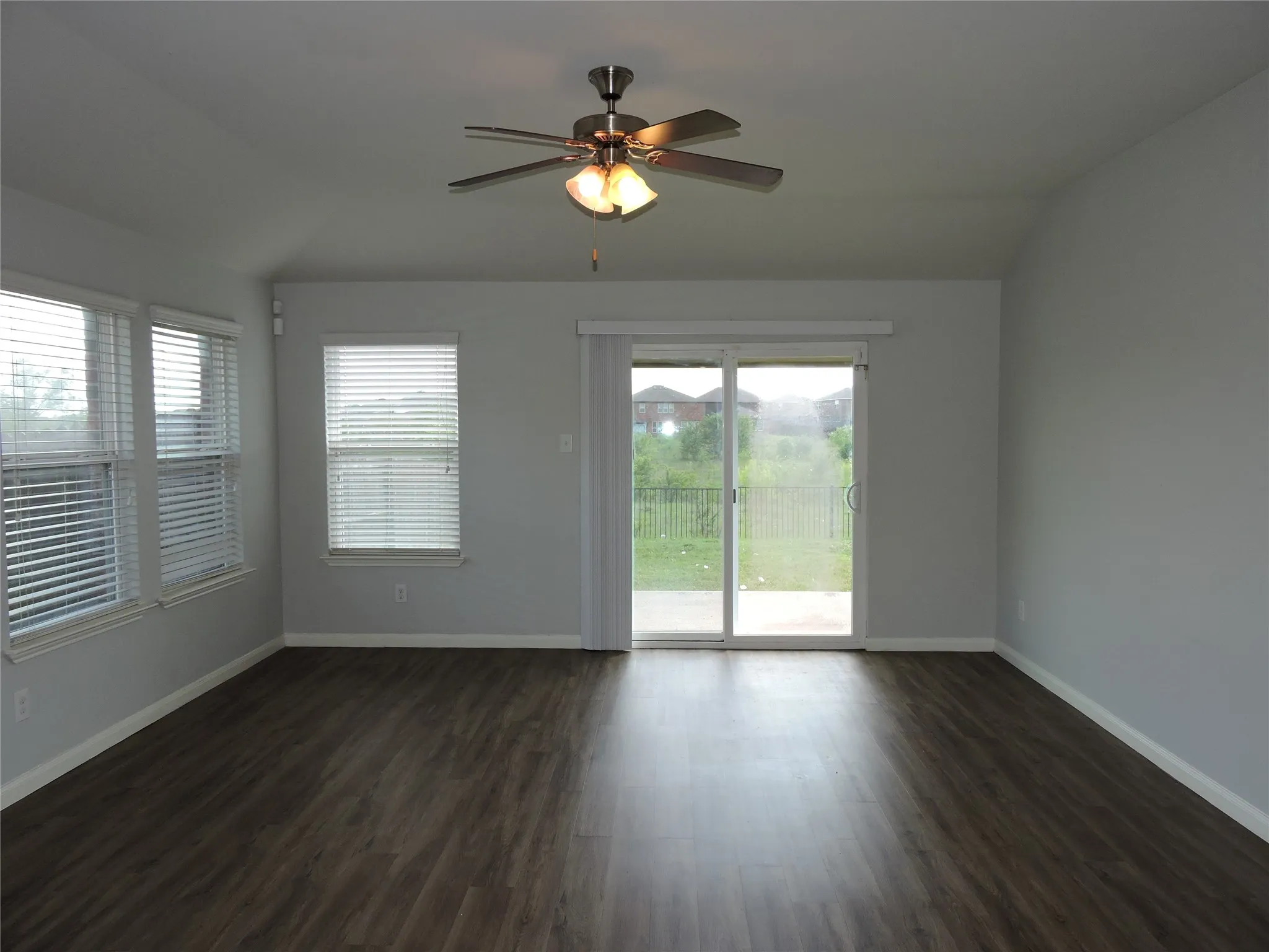 This living area features rich dark flooring, light-colored walls, and a ceiling fan with integrated lighting