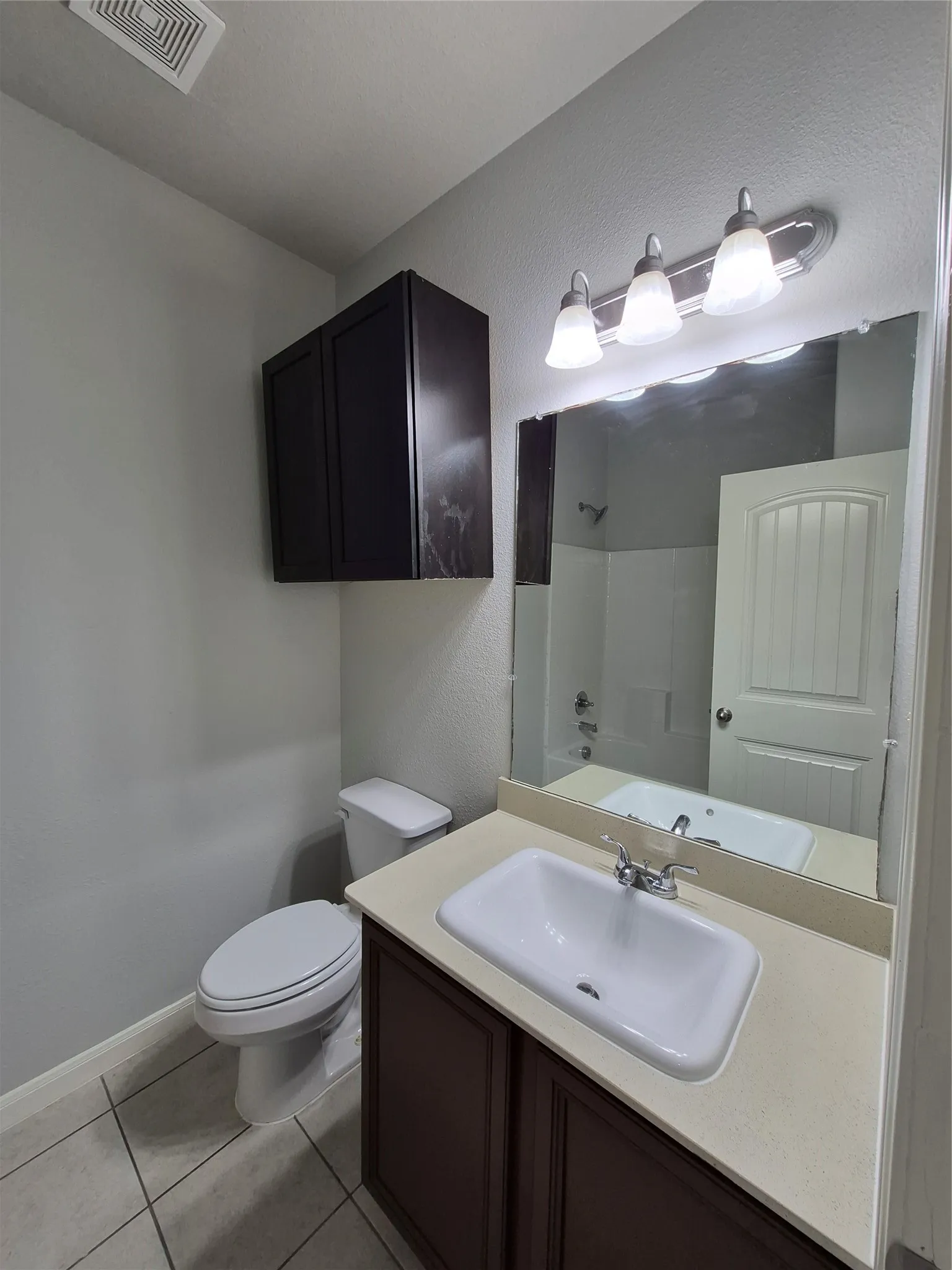 Bathroom featuring a vanity with a light-colored countertop, a sink with a chrome faucet, and a mirror with overhead lighting