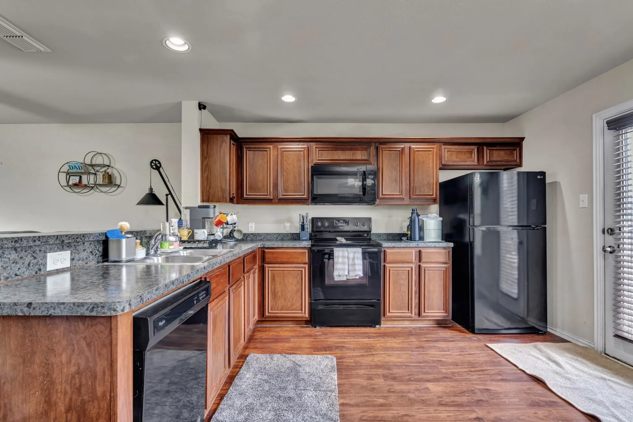 The property features a kitchen with wood cabinets, dark countertops, and dark appliances including a refrigerator, oven, and microwave