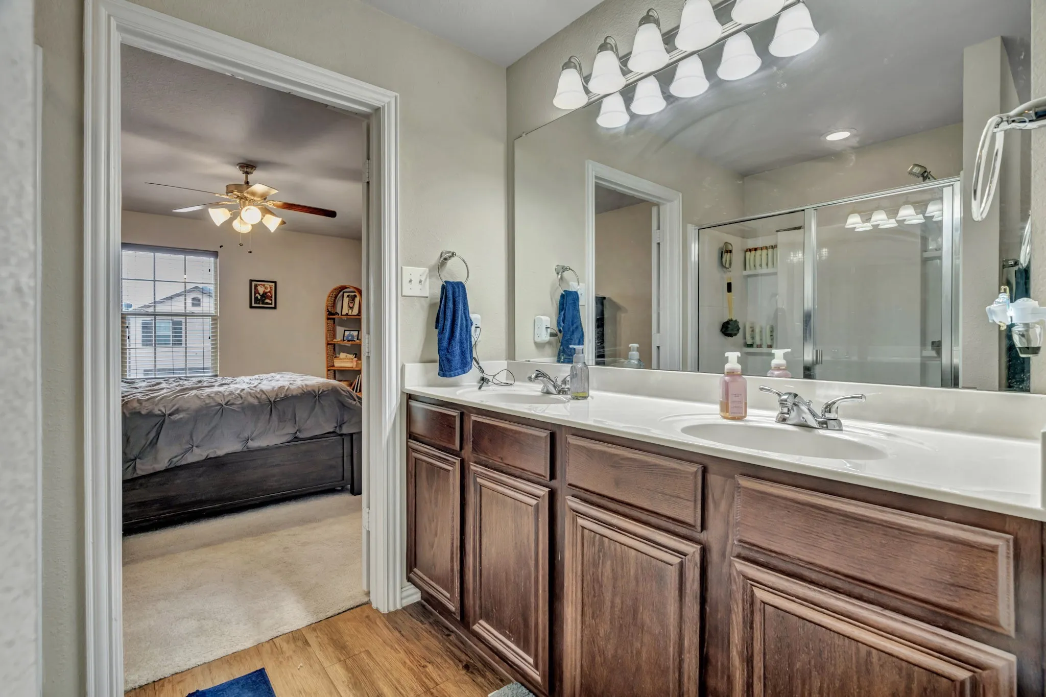 The bathroom features a dual vanity with dark wood cabinetry, a light-colored countertop, and a large mirror