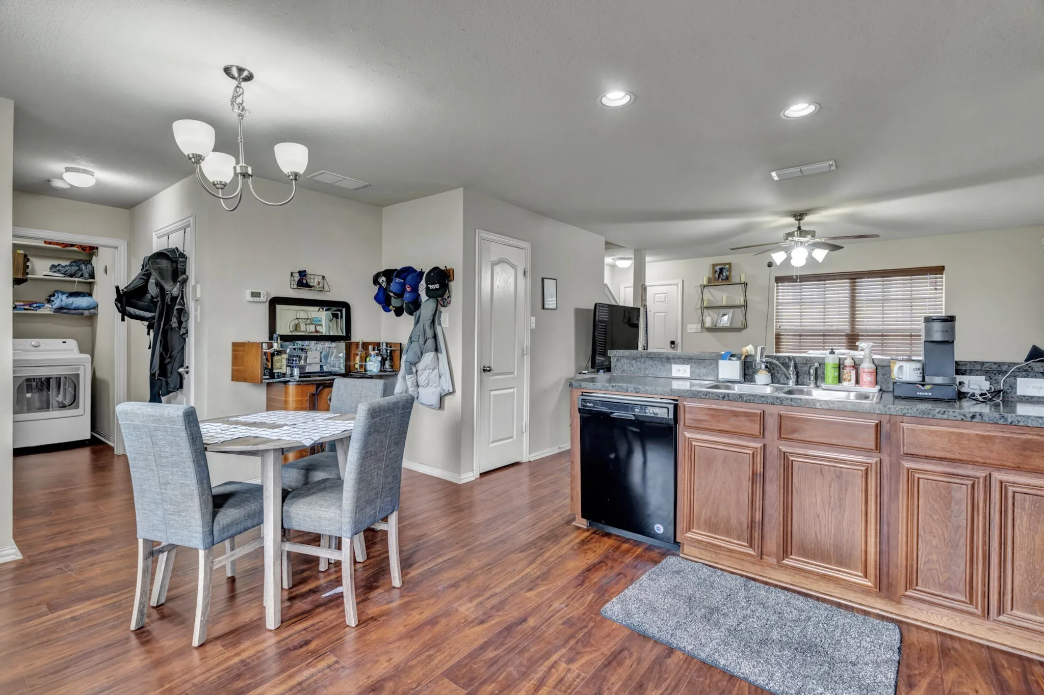 Open concept living area featuring hardwood flooring, a dining area with a modern chandelier, and a kitchen island with stone countertops and a dishwasher